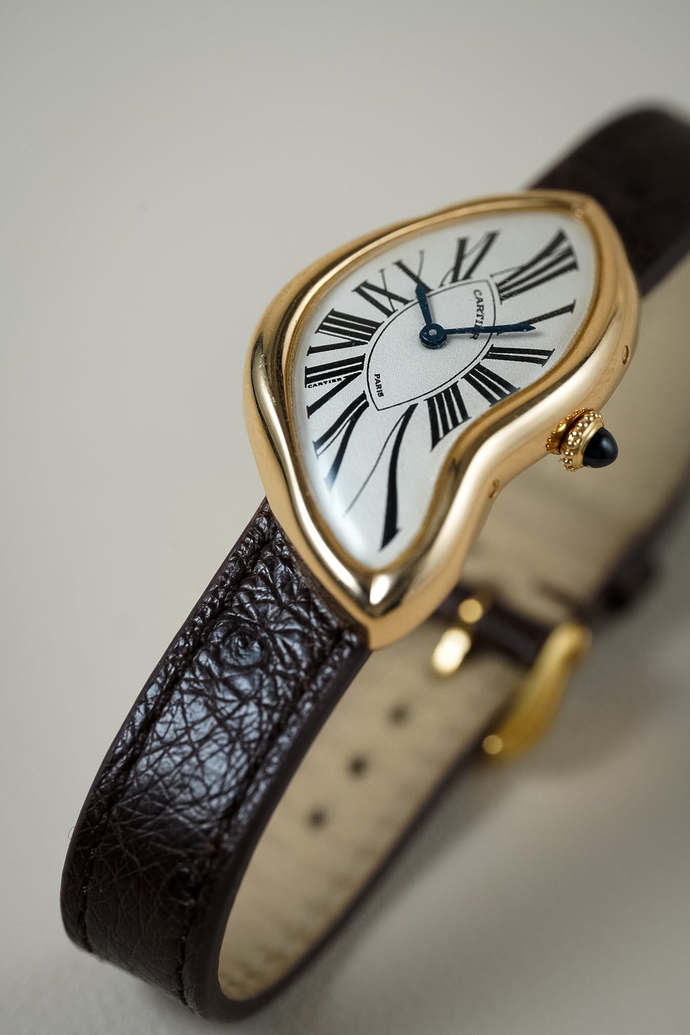 Gold watch with a roman numeral dial on a brown strap