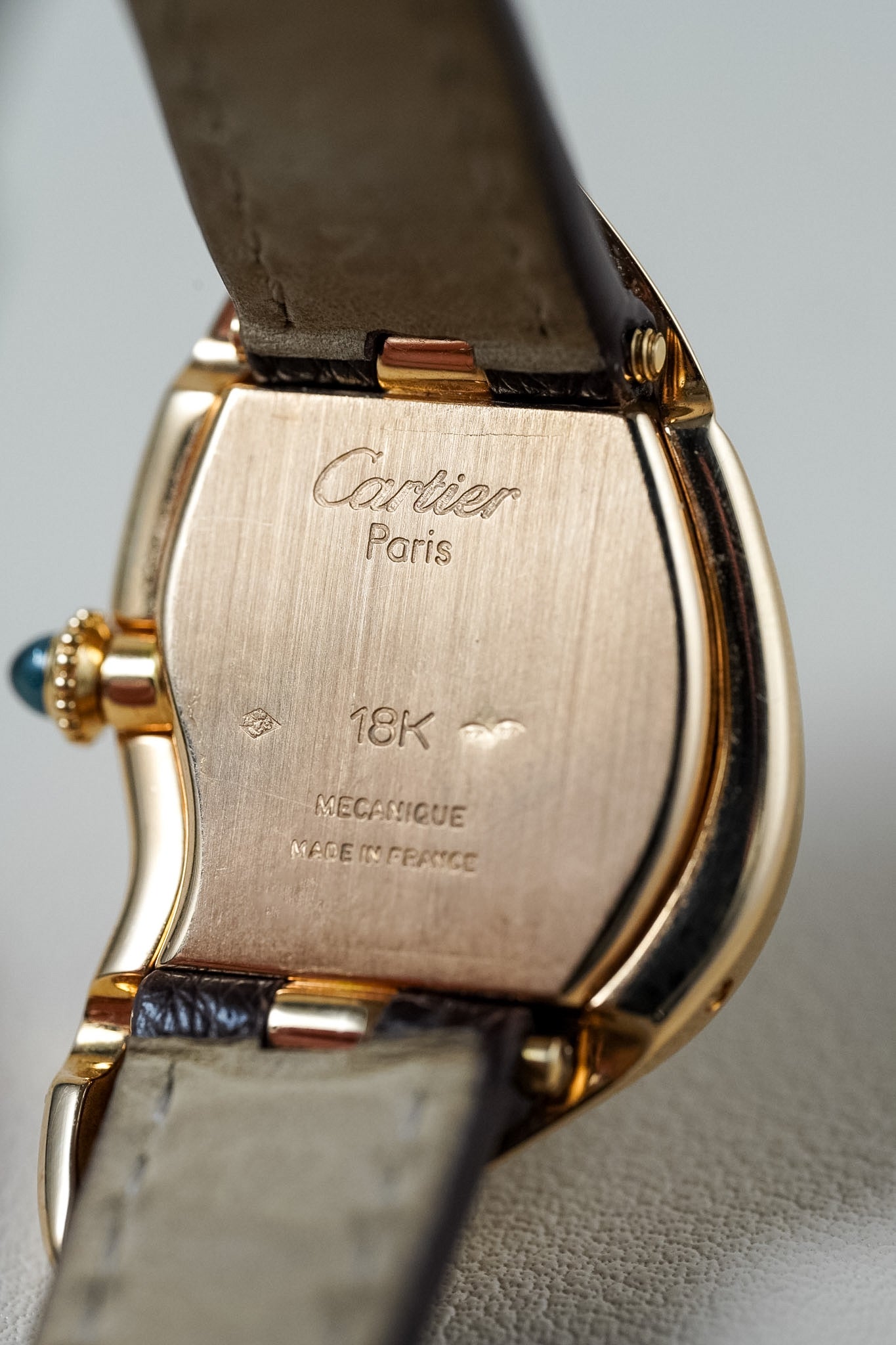 Back of a uniquely shaped gold Cartier watch 