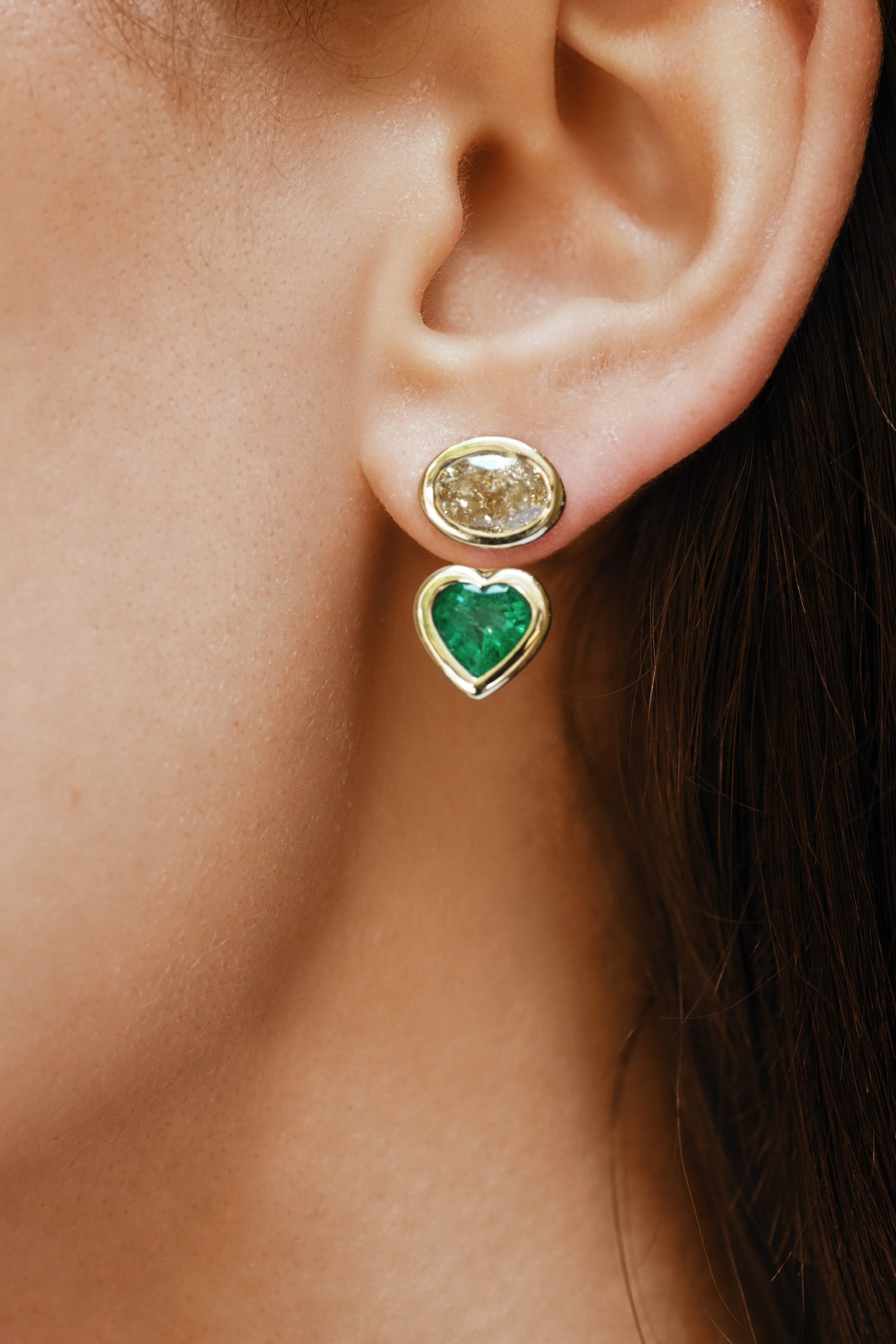 Close-up of an ear wearing a gold earring with a green gemstone.