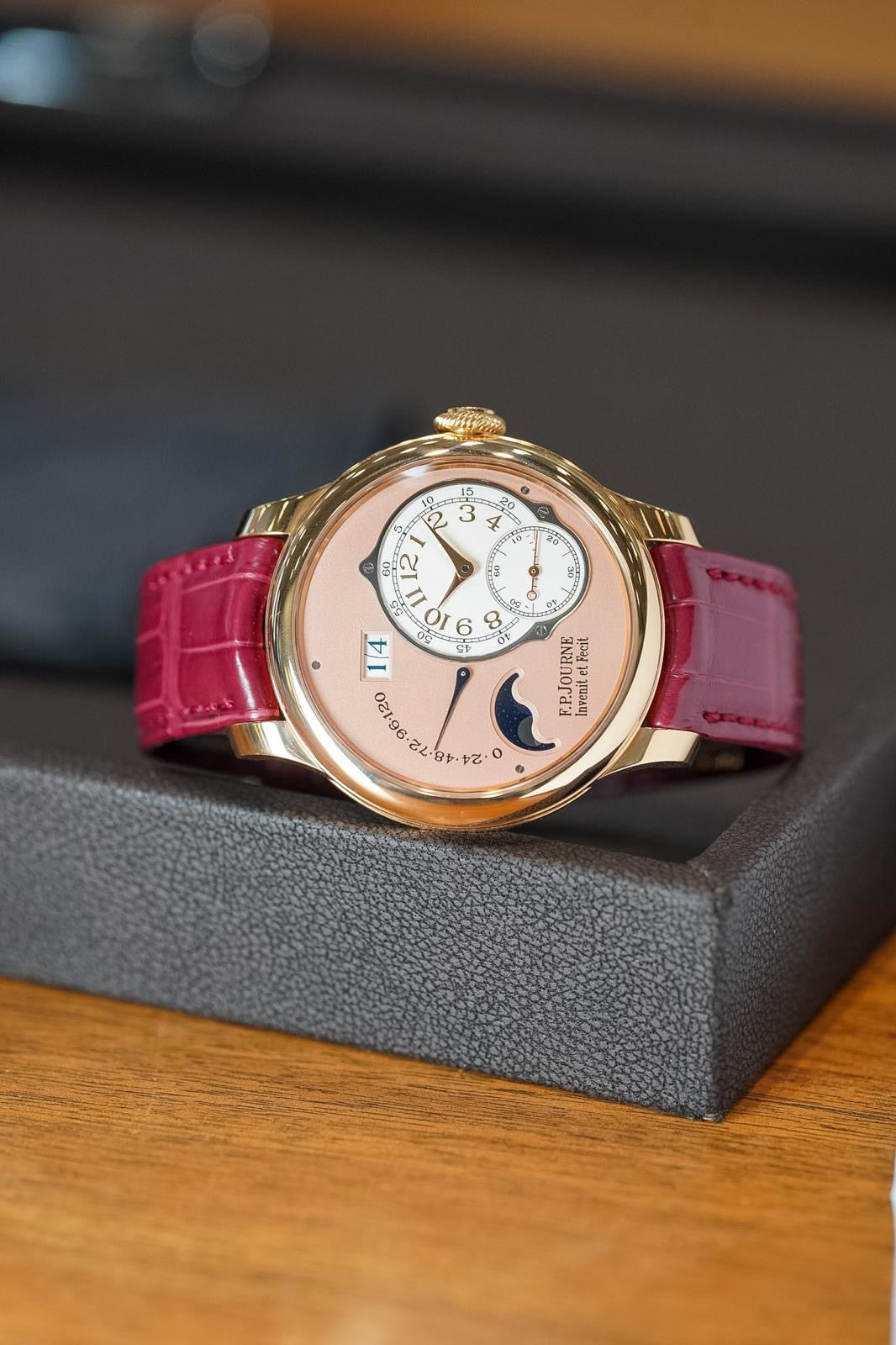 Luxury watch with pink strap on a wooden surface