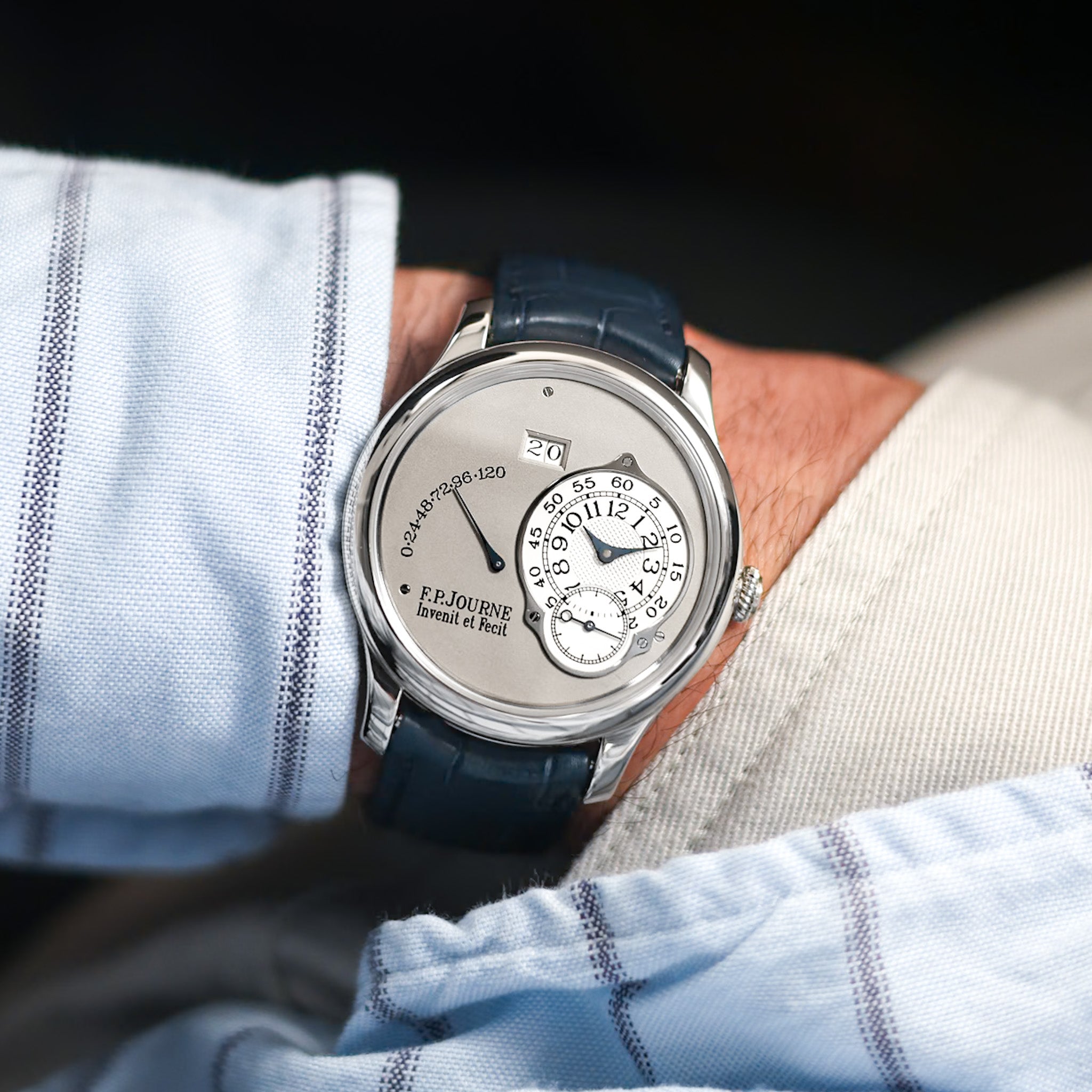 Luxury watch with detailed face on a person's wrist, wearing a light blue shirt.