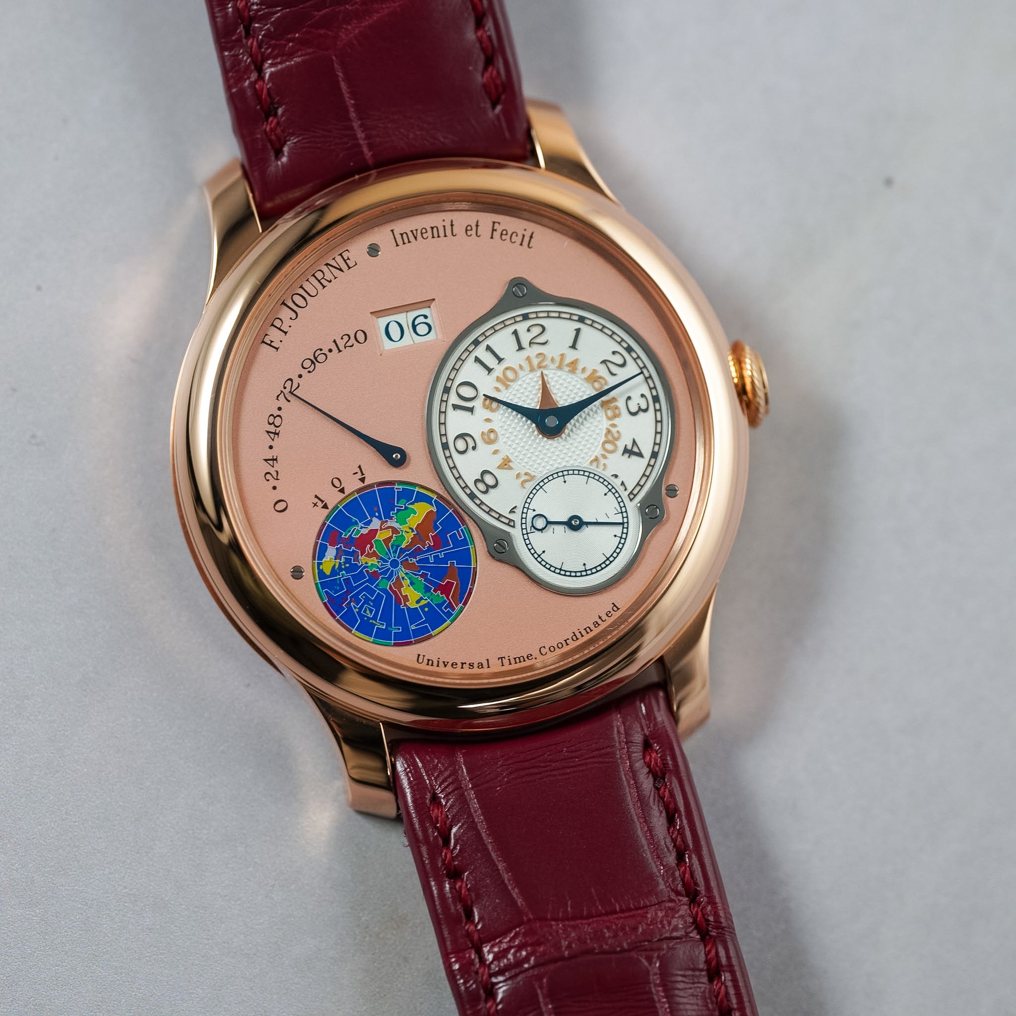 Luxury watch with a red leather strap on a light gray background