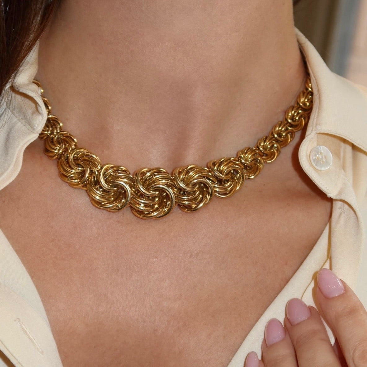 Gold chain necklace worn by a person with a blurred background