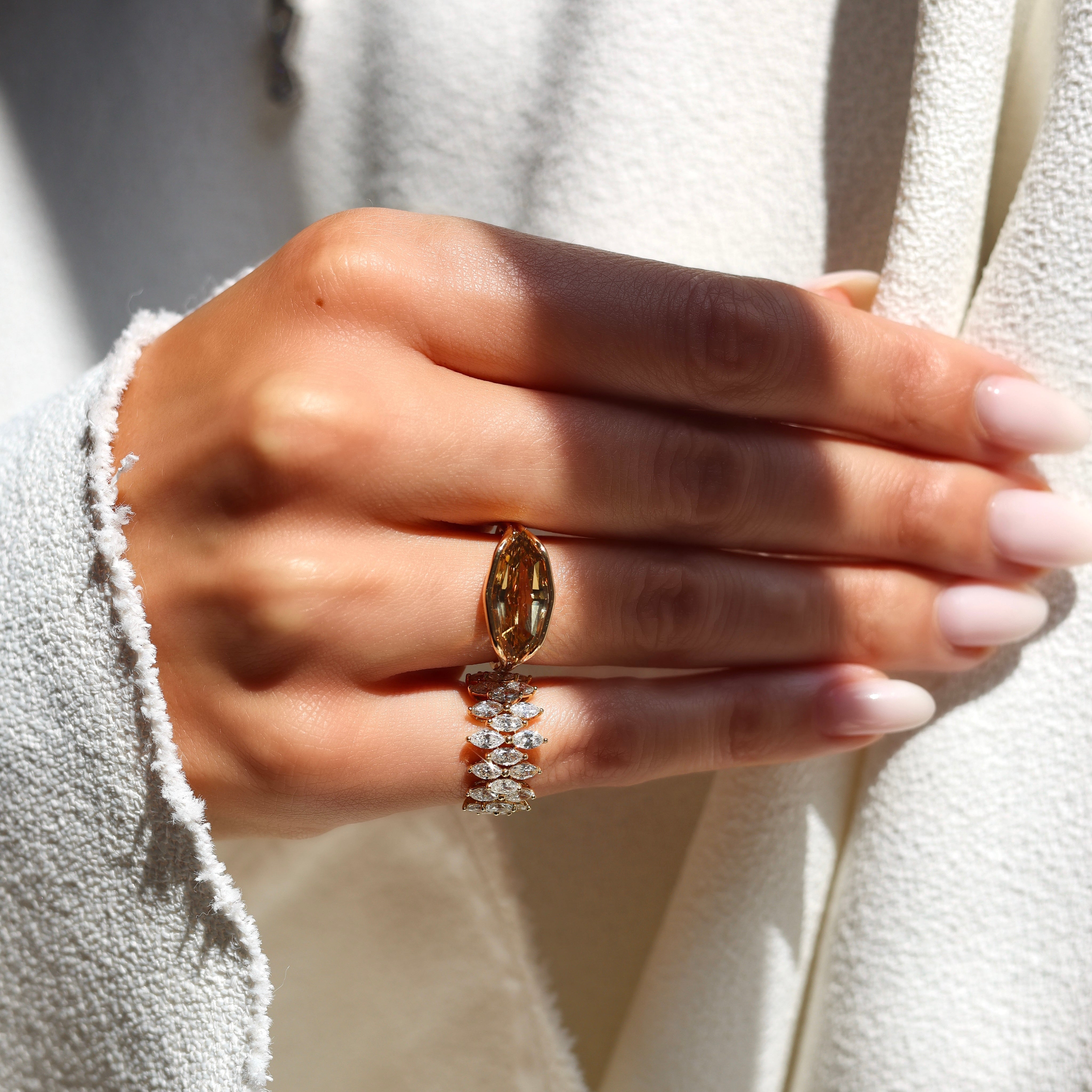 Gold ring with a large brown gemstone on a white background on figure
