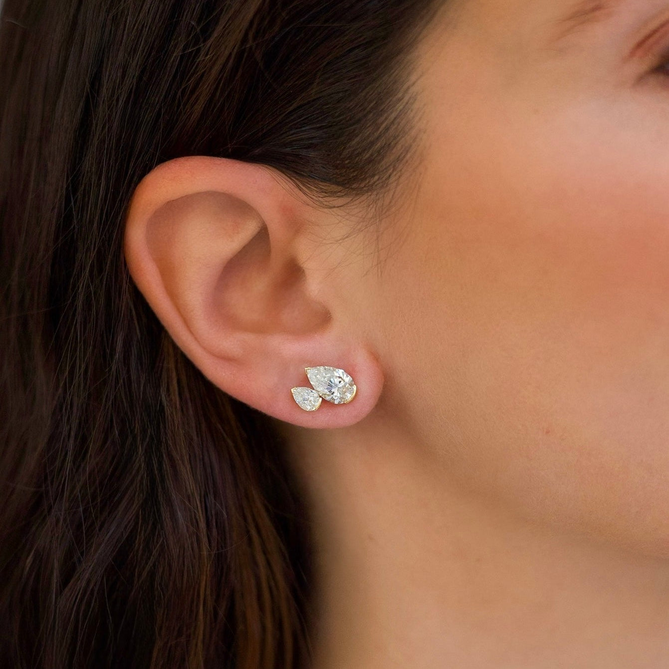 Close-up of an ear wearing a silver earring with a blurred background