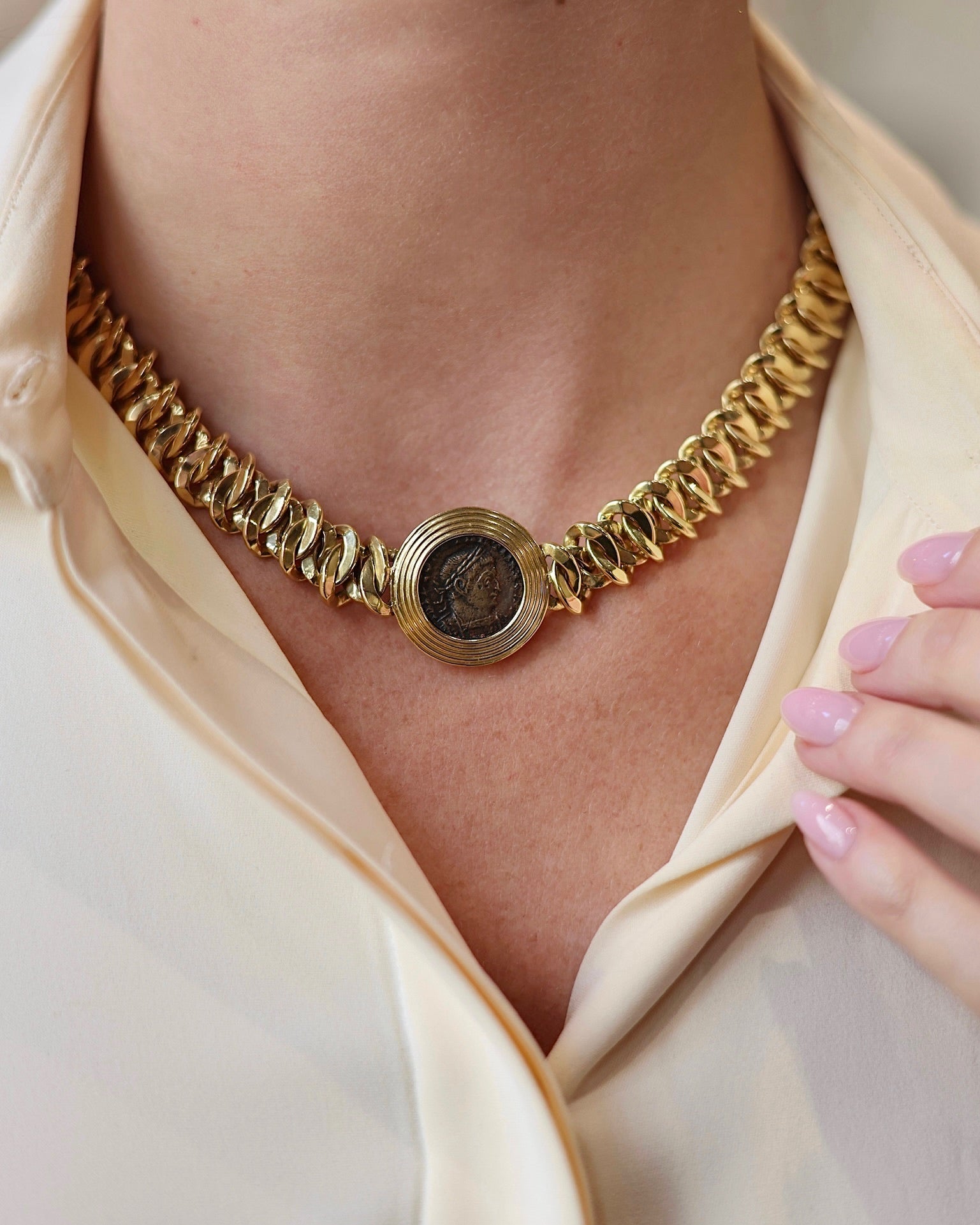 Gold necklace worn by a person with a blurred background