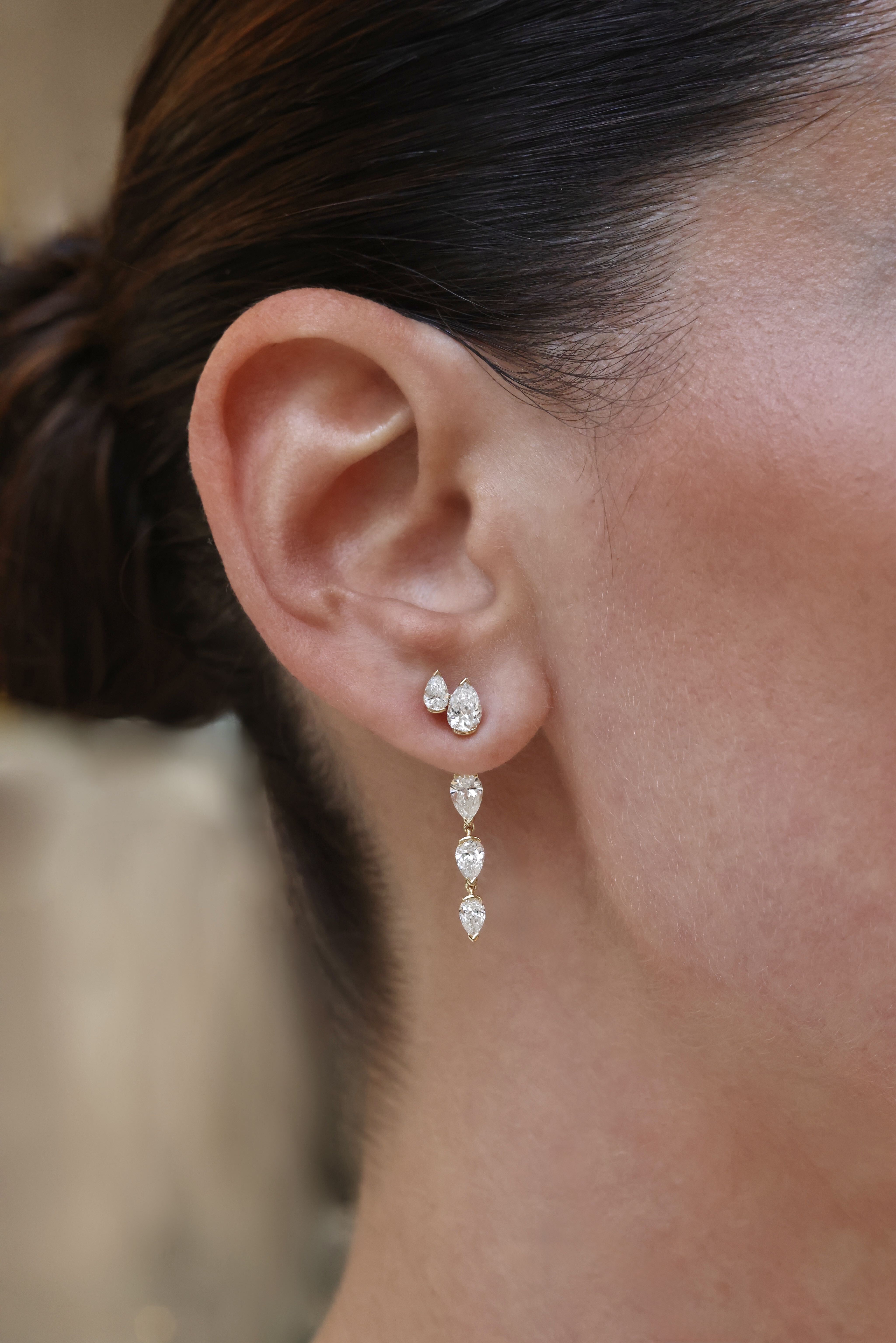 Model wearing pear-shaped diamond stud earrings paired with a graduated pear diamond drop jacket in 18K yellow gold