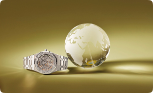 silver watch next to a translucent globe in front of a golden glowing background