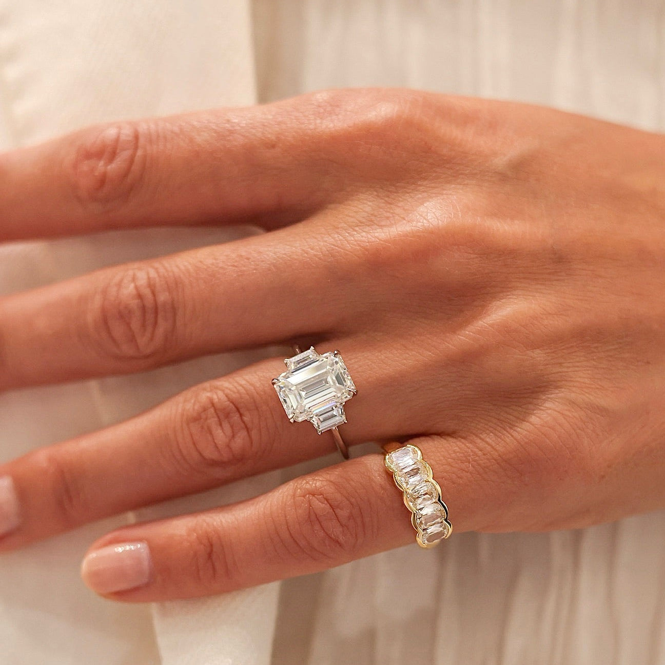 Close-up of a hand wearing two diamond rings on a light background