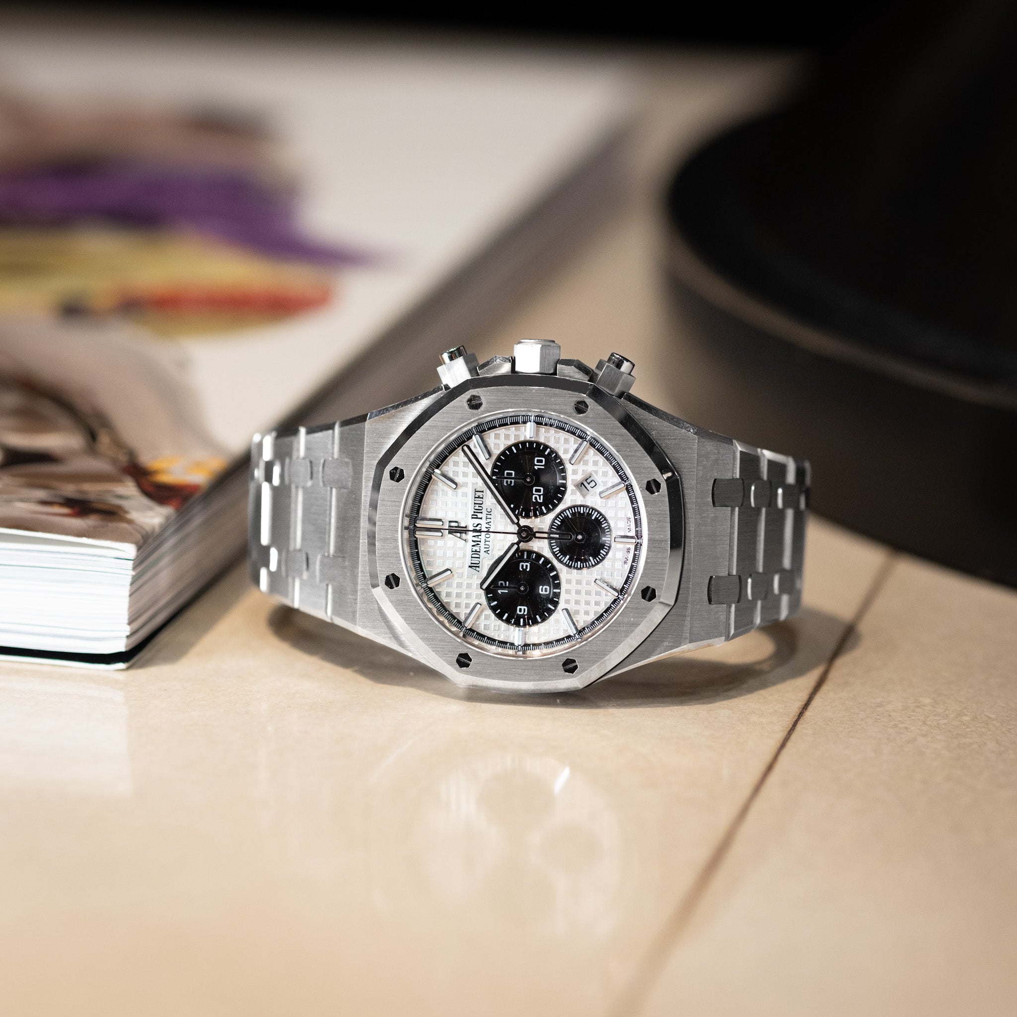 Steel chronograph with a white dial on a table