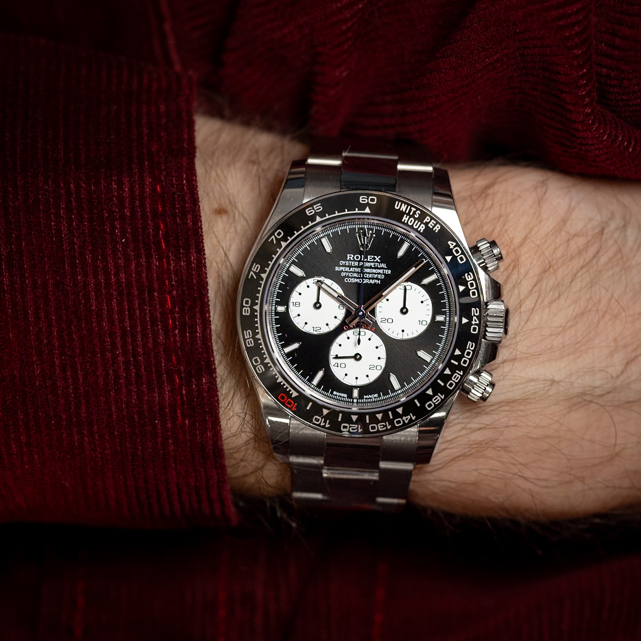 Silver and black watch on a wrist with a red sleeve