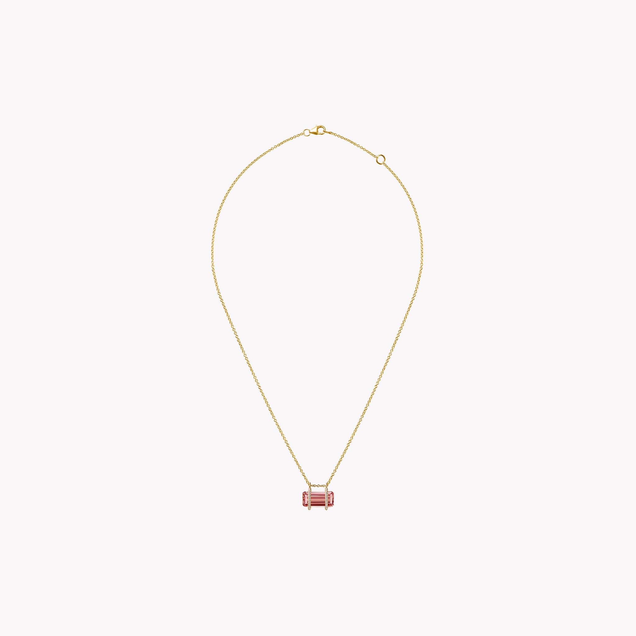 Gold necklace with a pink pendant on a light gray background
