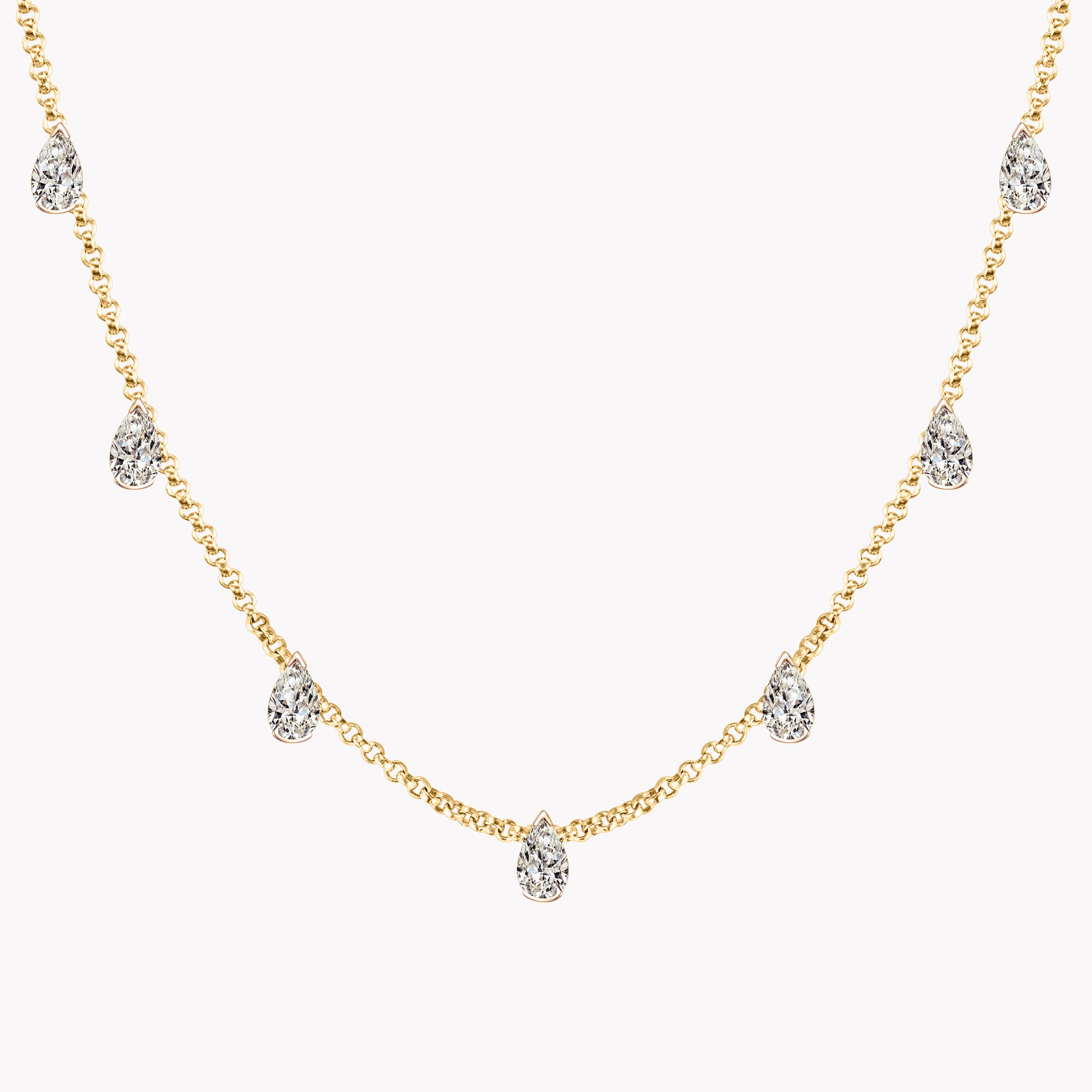 Customizable pear diamond choker necklace in 18K yellow gold featuring seven bezel-set diamonds on a delicate chain. Close up.