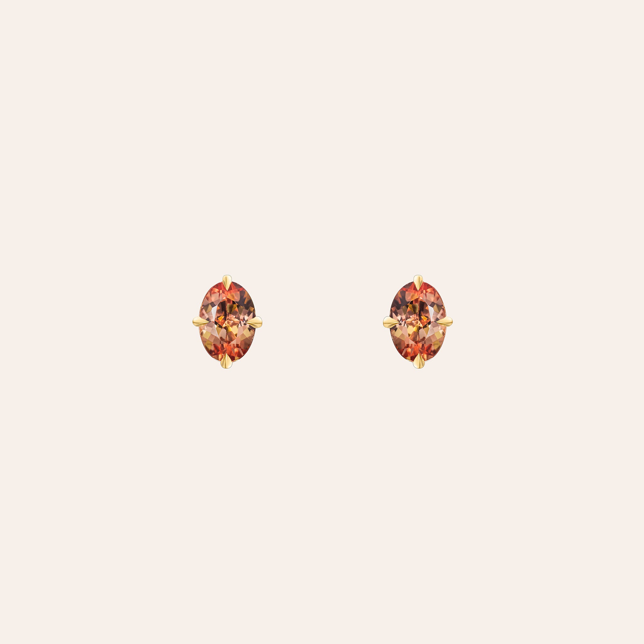 Sloane Oval Topaz Studs in 18K yellow gold, with orange oval-cut topaz held in compass-set prongs, shown against a cream background.