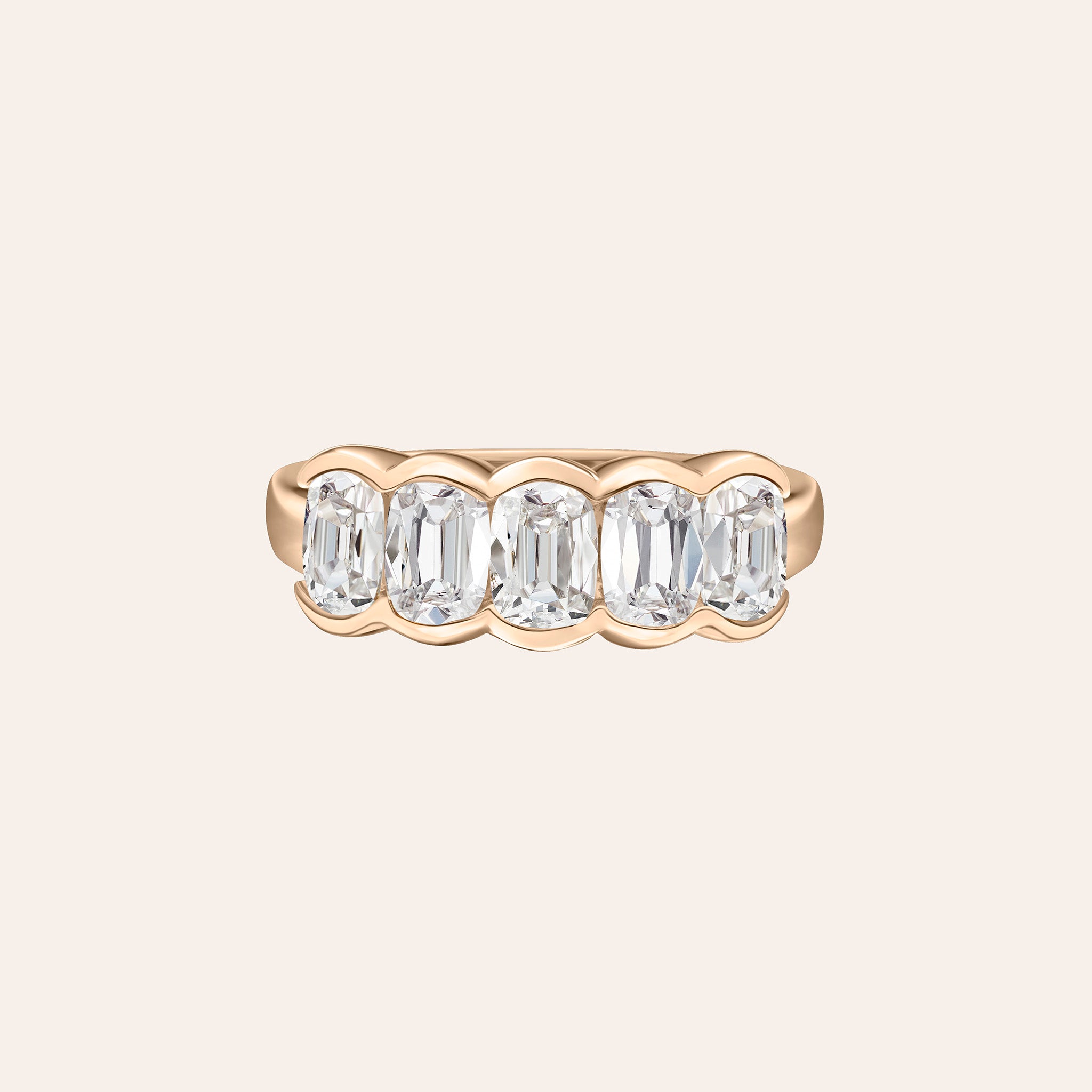 A rose gold five-stone ring featuring bezel set cushion-cut diamonds centered on a light cream background.