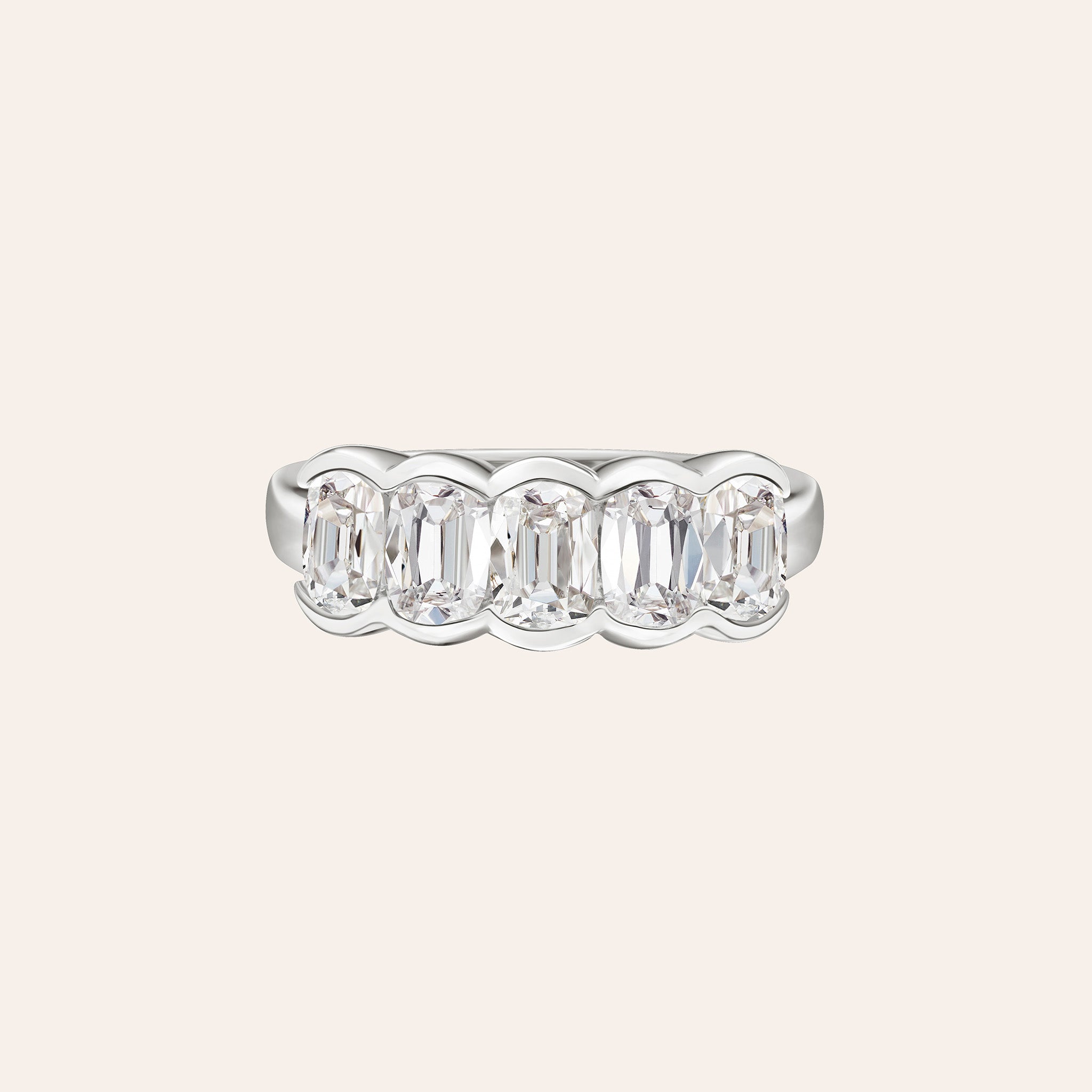 A white gold five-stone ring featuring bezel set cushion-cut diamonds centered on a light cream background.