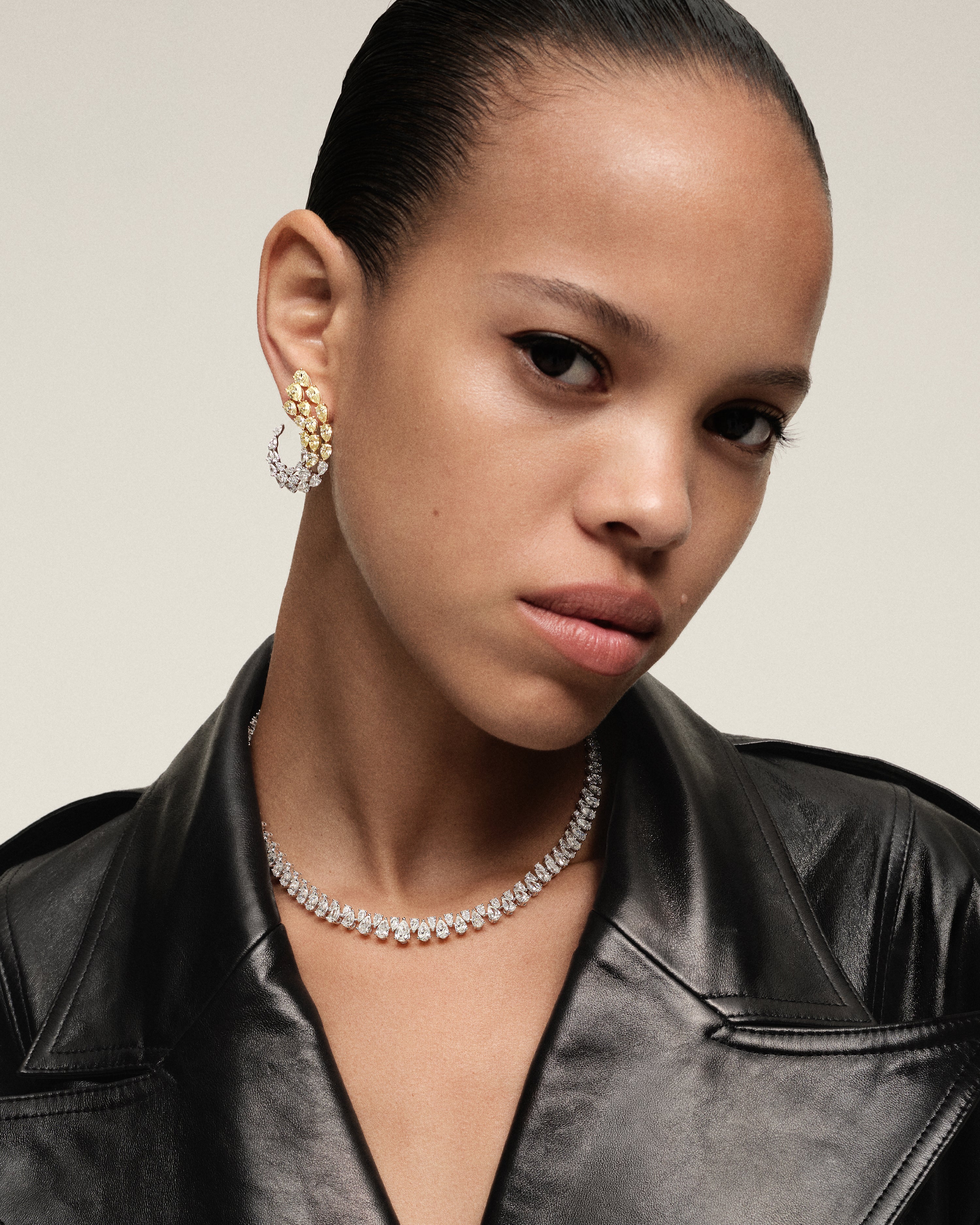 Model wearing pear-shaped yellow and white diamond hoop earrings with diamond necklace