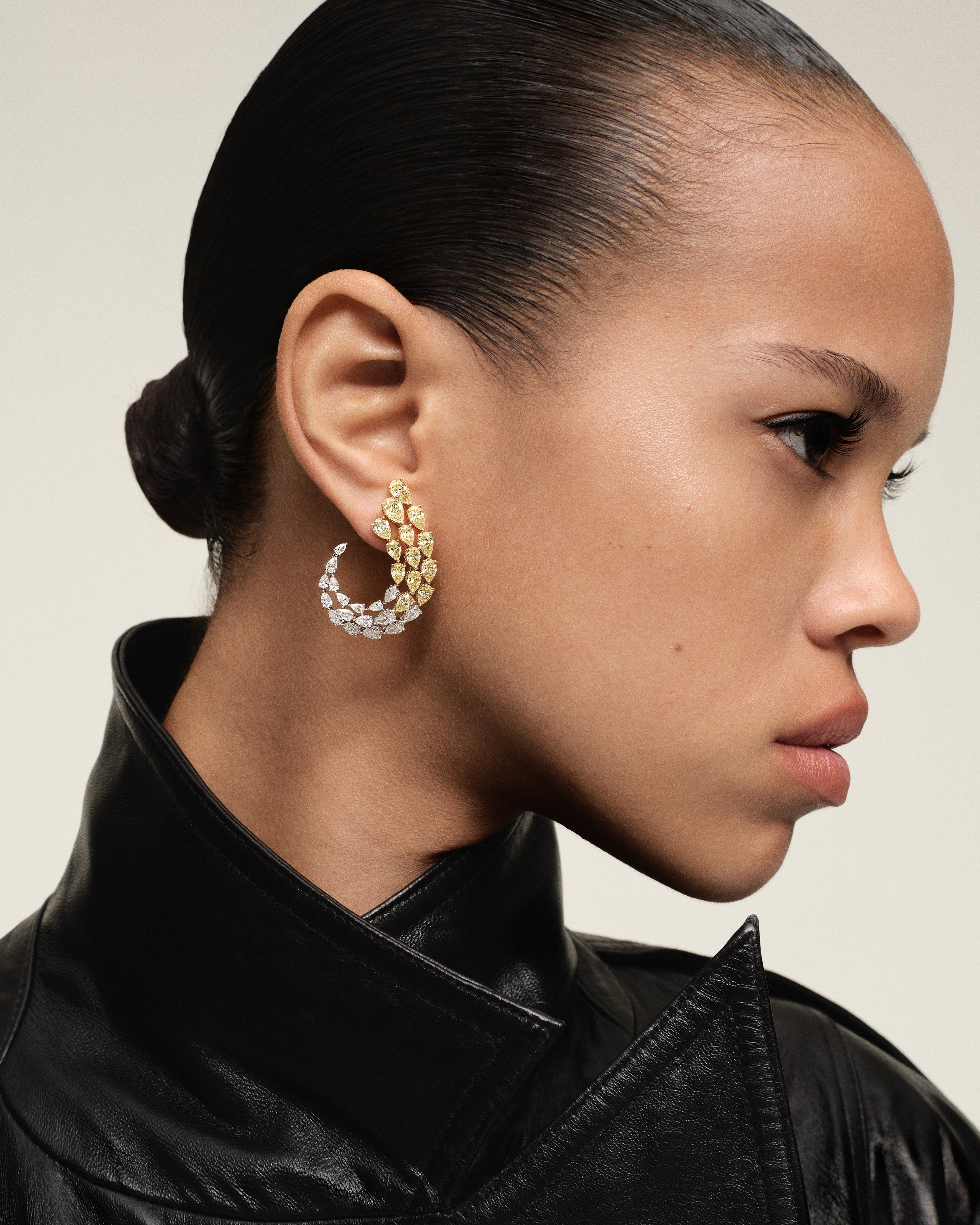 Side profile of model wearing luxury pear diamond hoop earrings in mixed gold