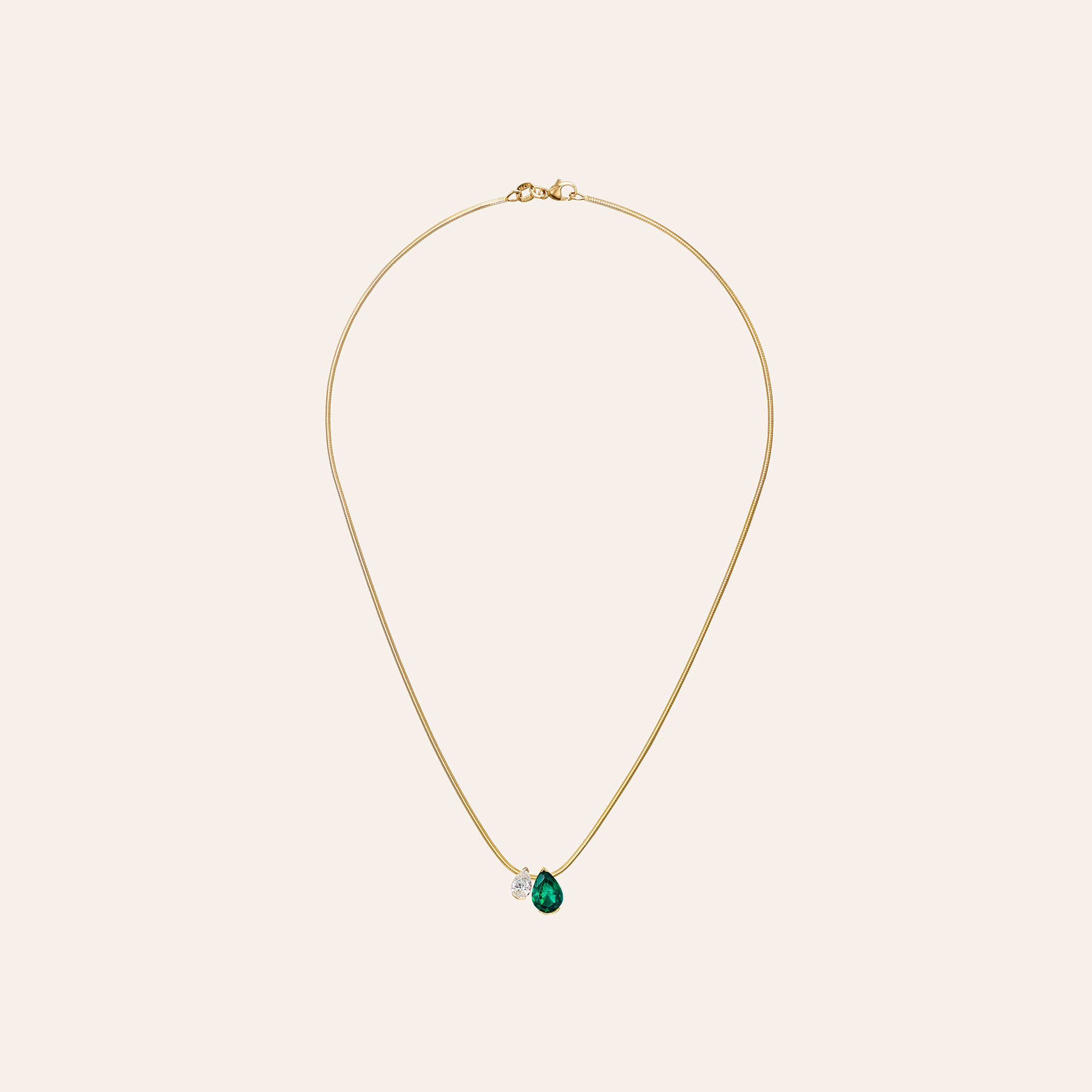 Close-up of the Emerald Muse Duo Pendant showing the pear emerald and diamond in an 18k yellow gold half bezel setting