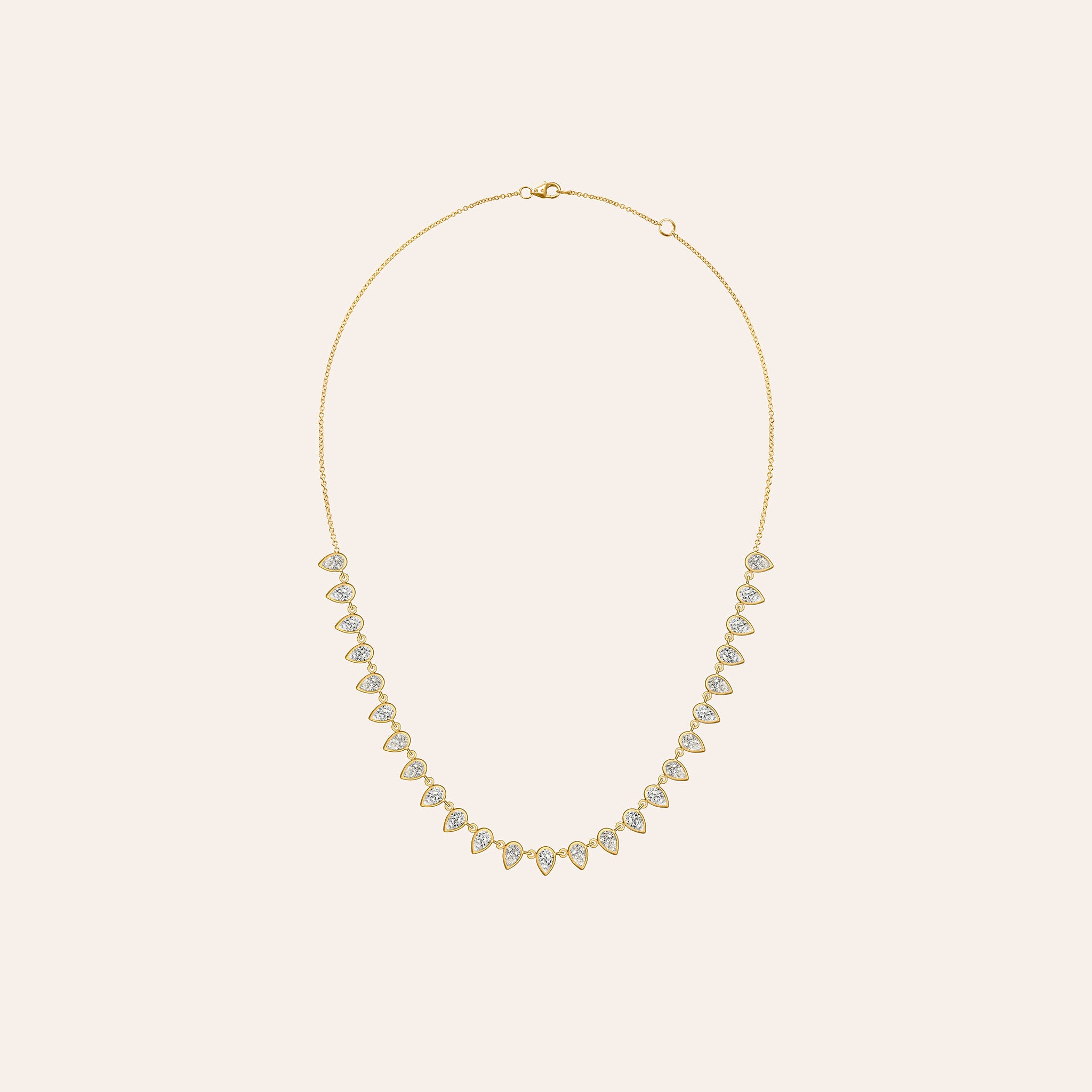 Alternate view of The Lena Pear Shape Necklace in 18K yellow gold, showing bezel-set pear-shaped diamonds in a fringe, against a cream background.