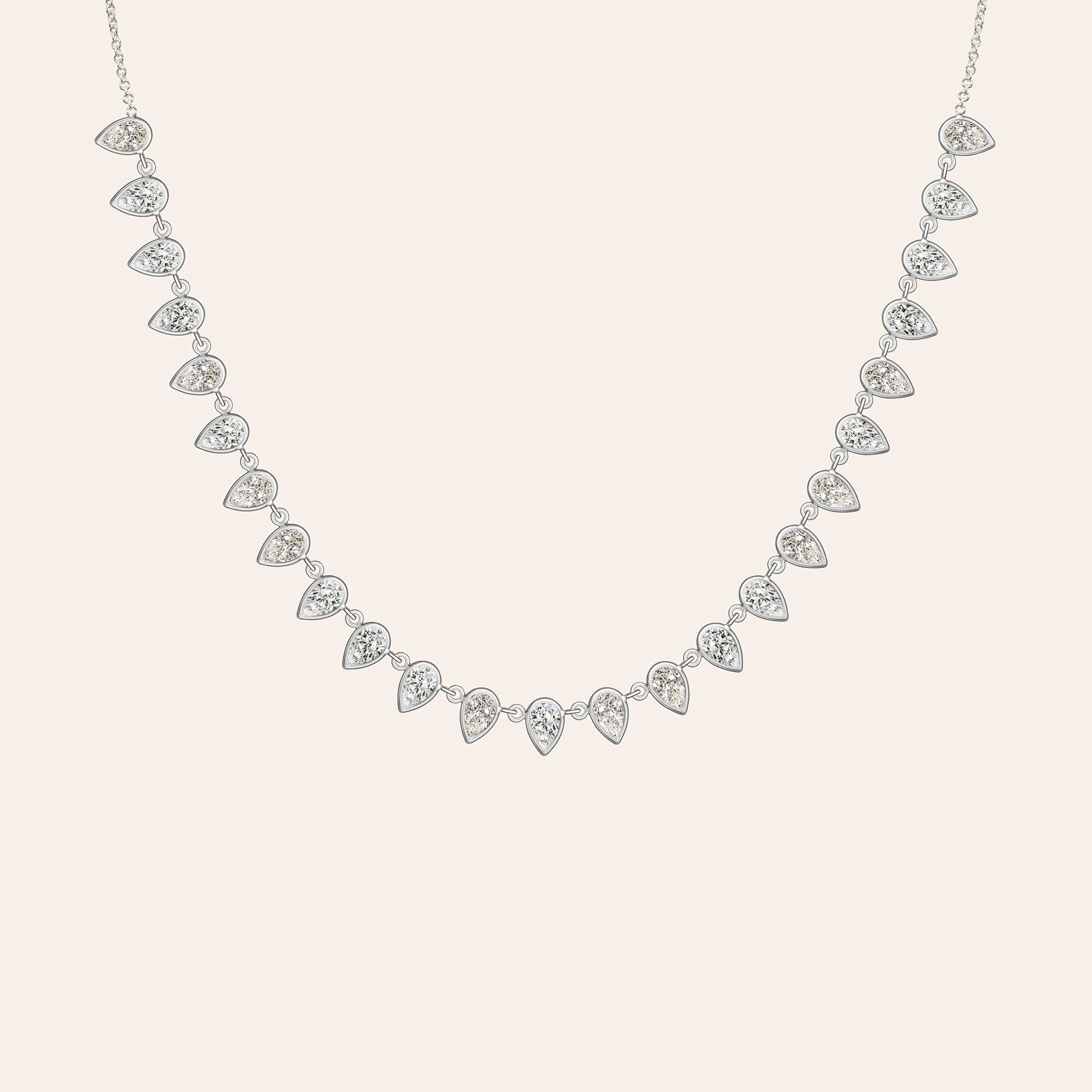 The Lena Pear Shape Necklace in 18K white gold, with a fringe of bezel-set pear-shaped diamonds, shown against a cream background.