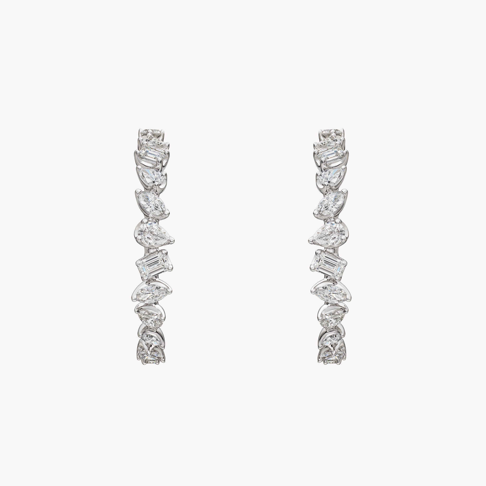 18K white gold hoop earrings with 2.73ct of pear, marquise, and emerald-cut diamonds arranged along the outer curve in a sculptural, modern design.