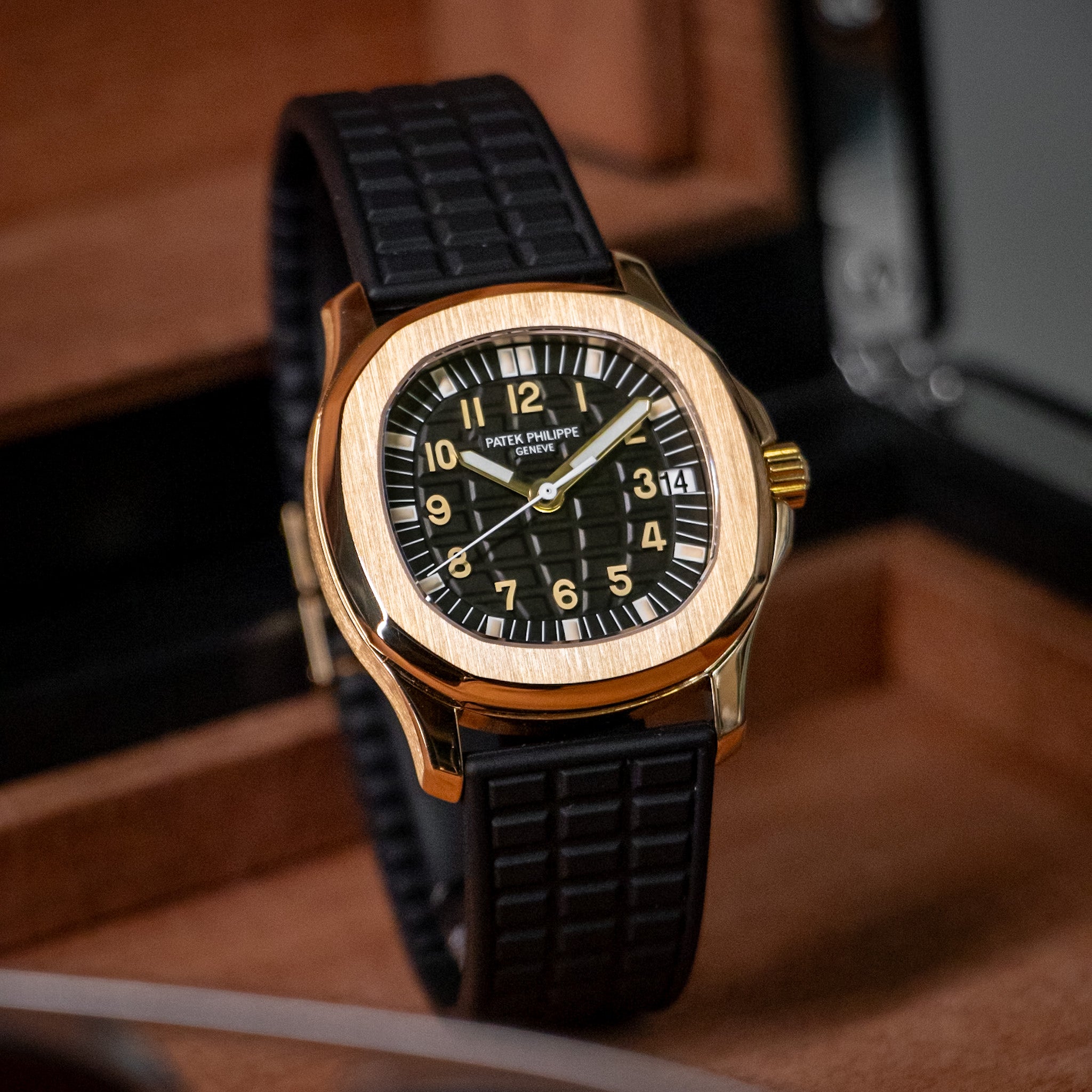 Luxury watch with black strap and gold case on a wooden surface