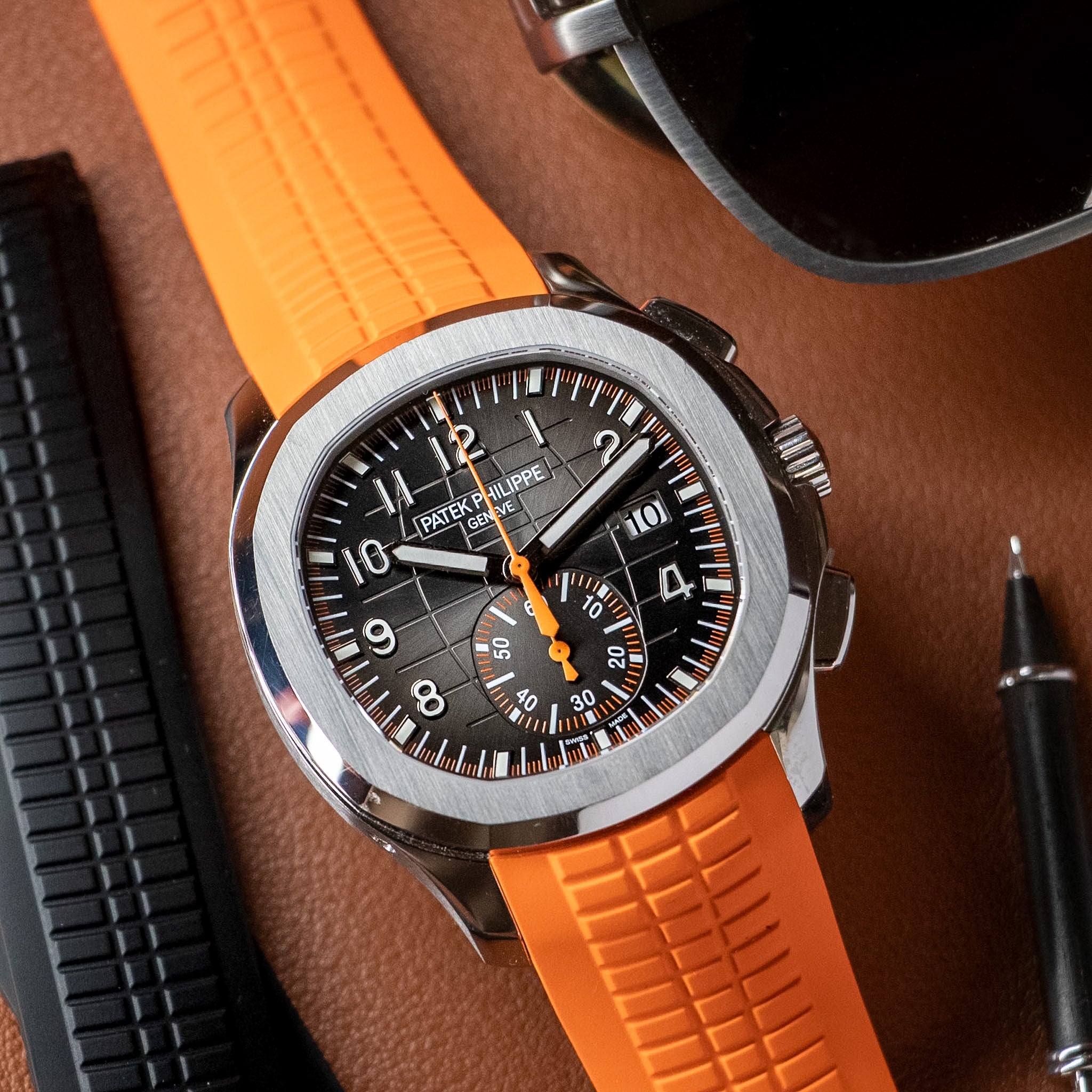 Watch with orange strap and black dial on a brown surface