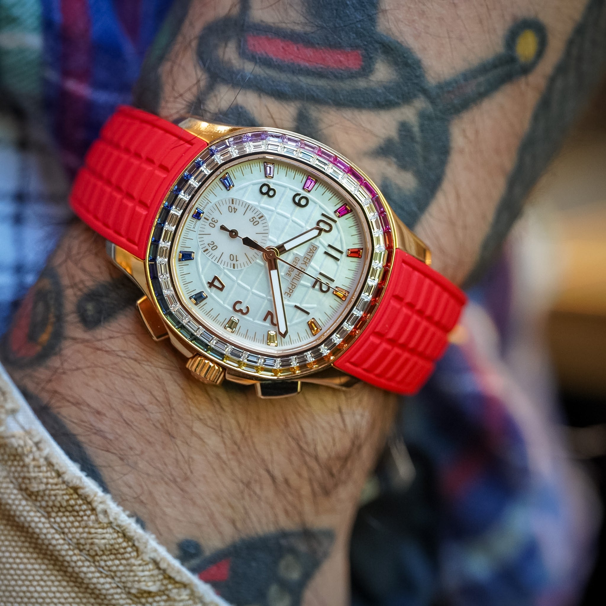 Red watch with gold case on a wrist with tattoos