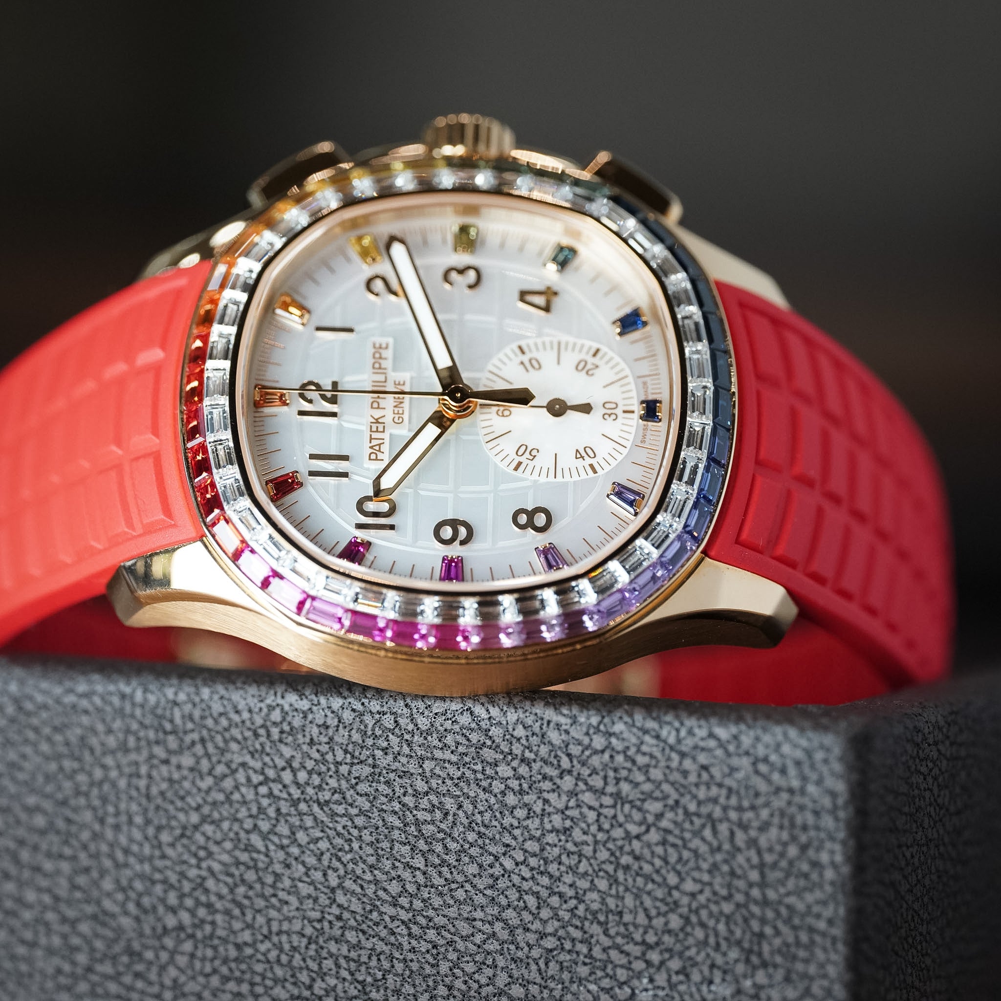 Watch with a red strap and colorful bezel on a textured surface
