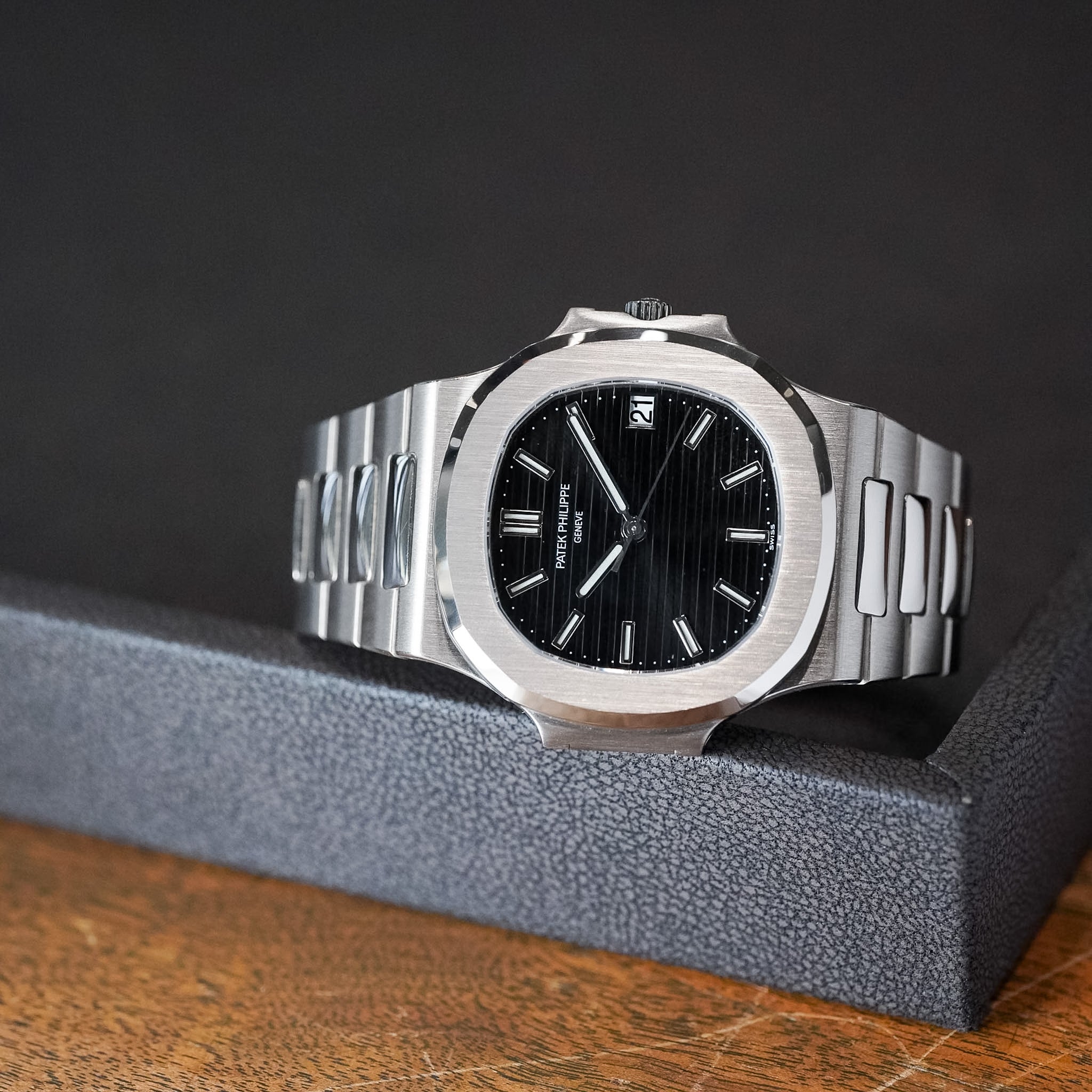 Silver watch with black dial on a dark background