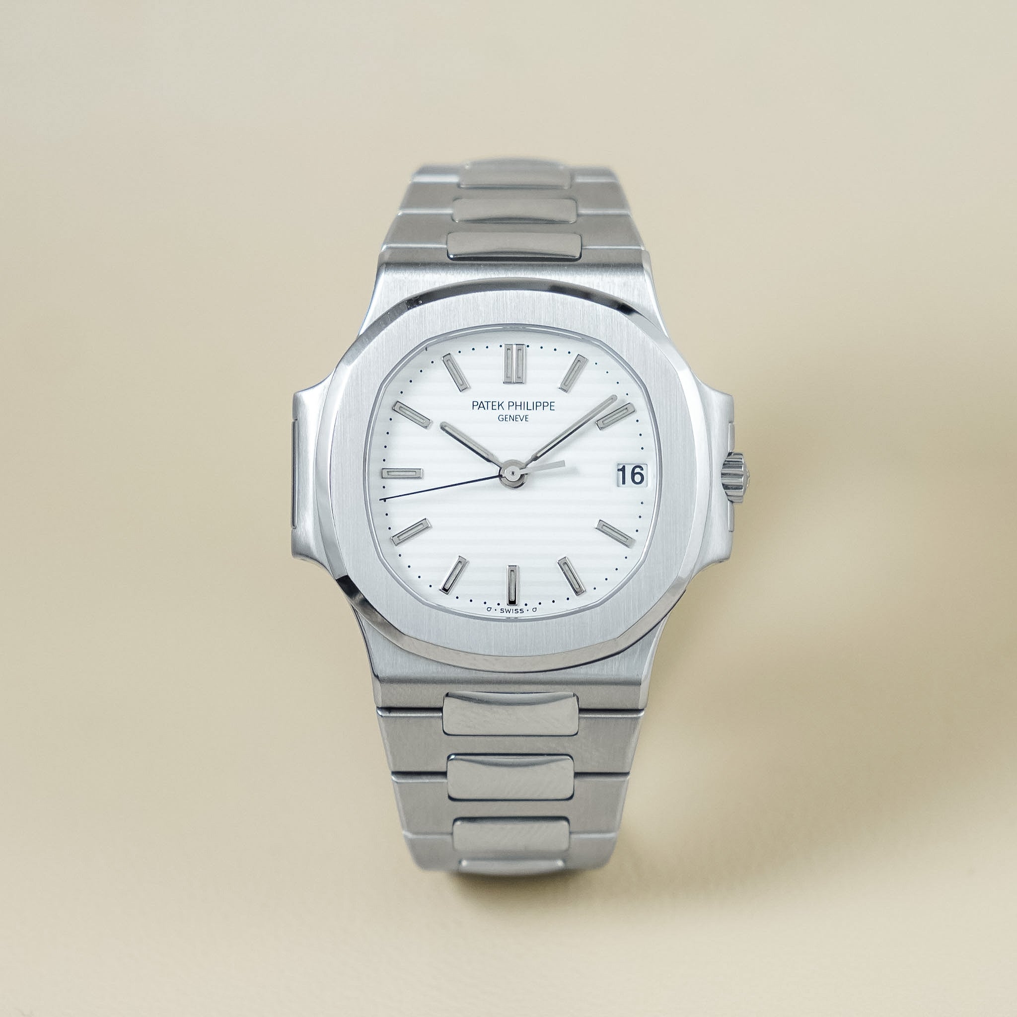 A stainless steel wristwatch with a white dial and integrated metal bracelet, photographed against a plain beige background. The brand name 'Peter Phillips' is visible on the dial.
