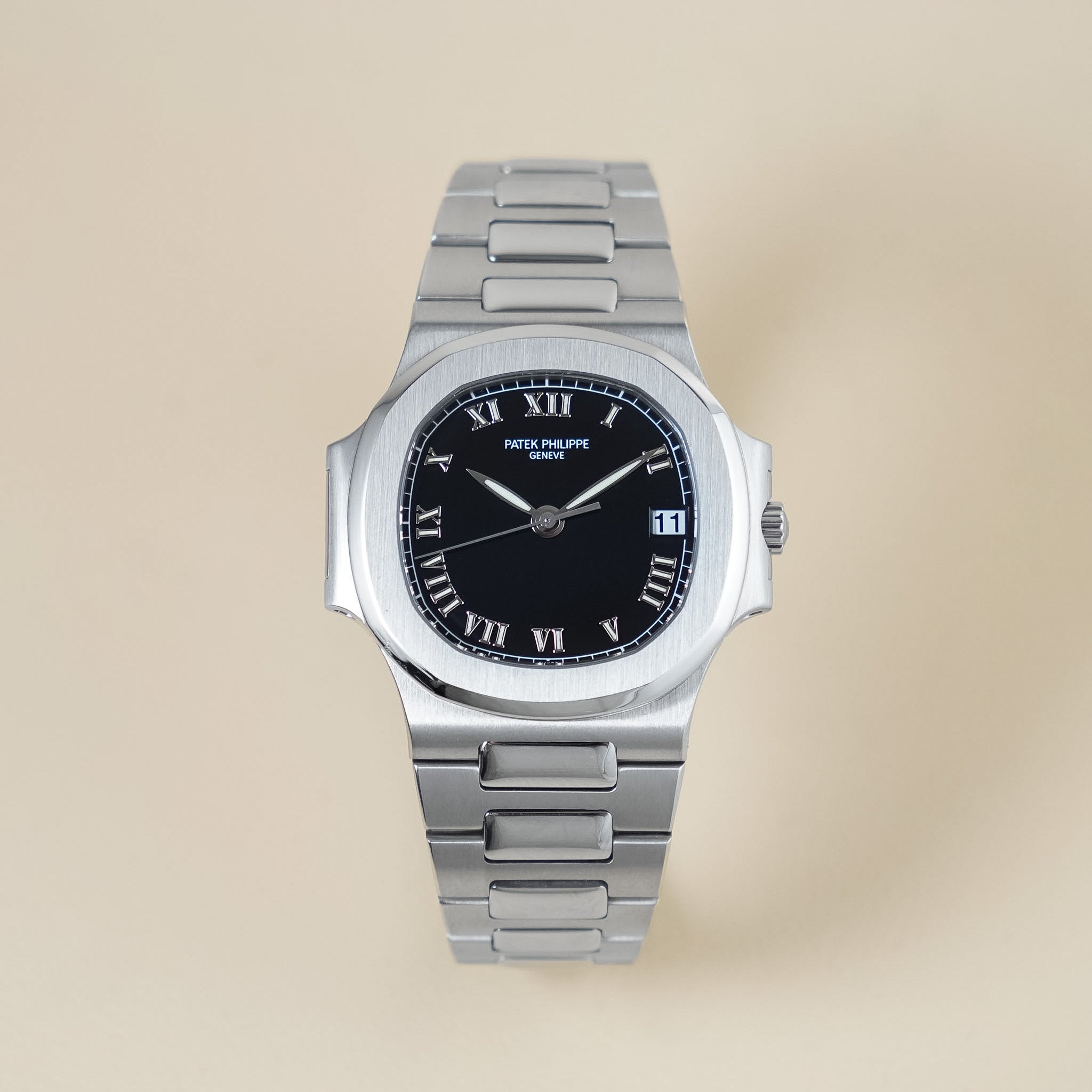 steel luxury watch with roman numeral dial on a cream background