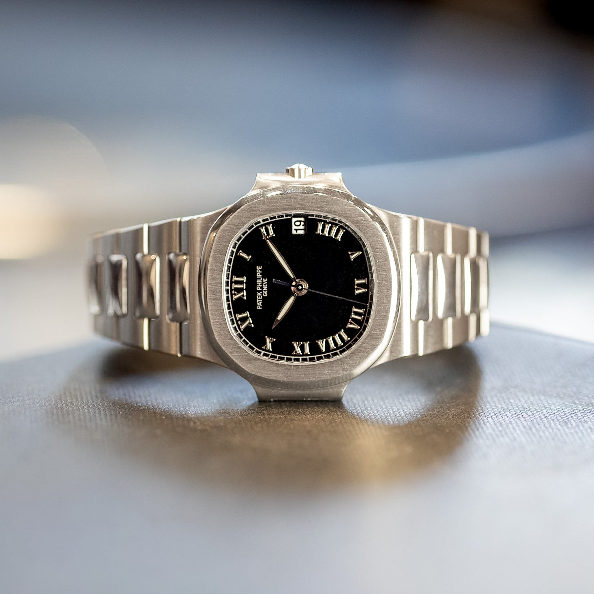steel watch with black dial laying sideways on a table