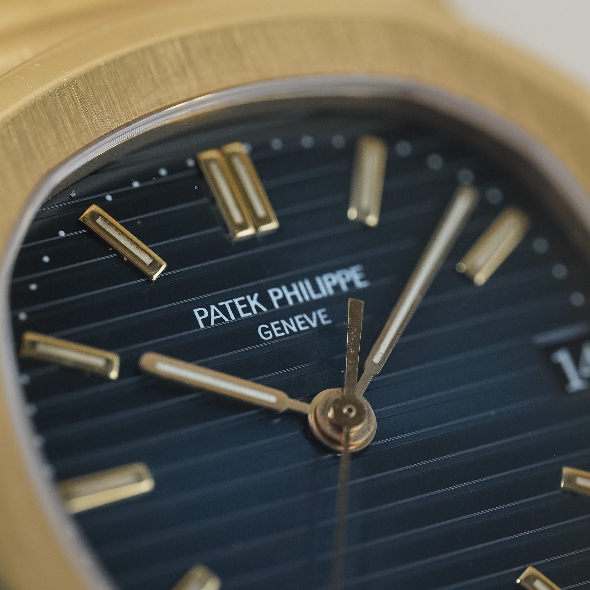 Close-up of a Patek Philippe watch face with gold accents and dark blue dial.