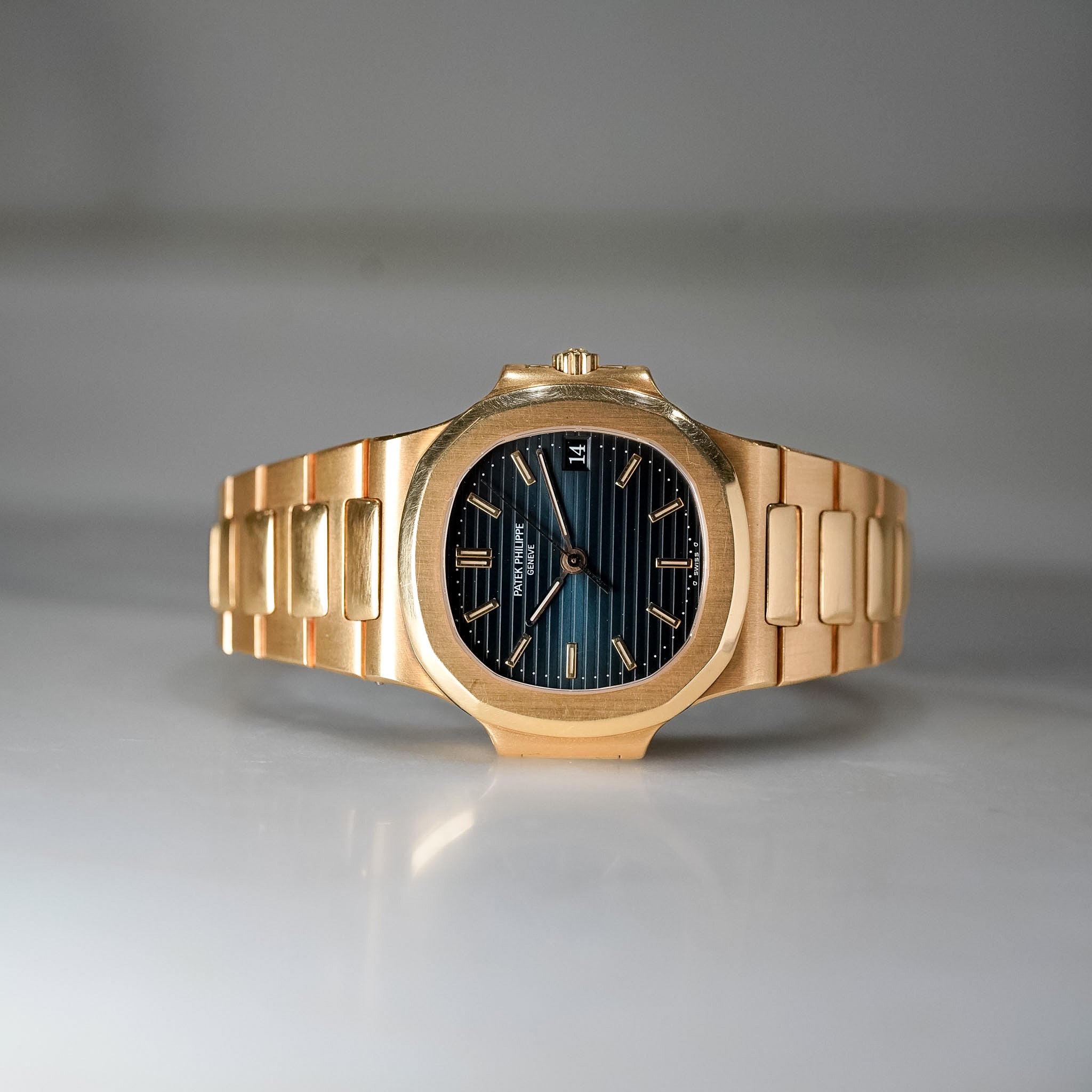 Gold wristwatch with a black face on a gray background