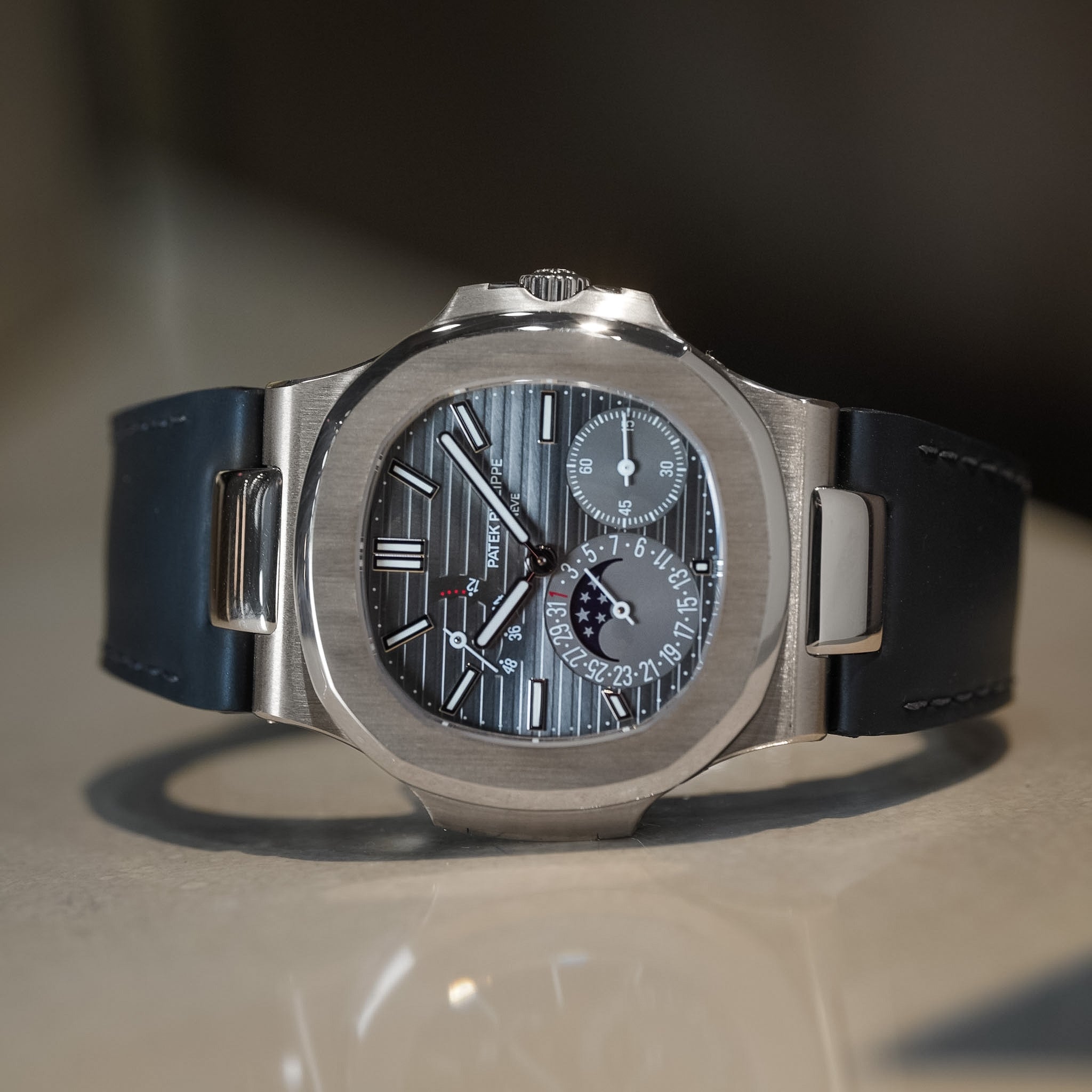 Luxury watch with a black strap on a reflective surface