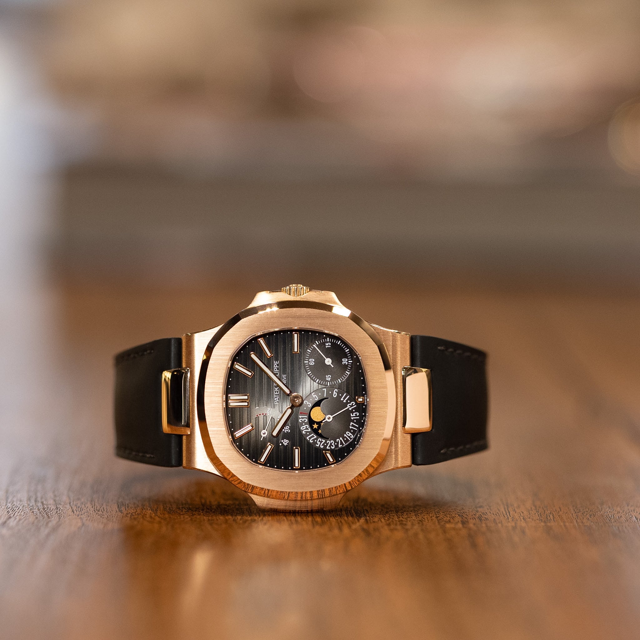 Luxury watch with black face and gold case on a wooden surface
