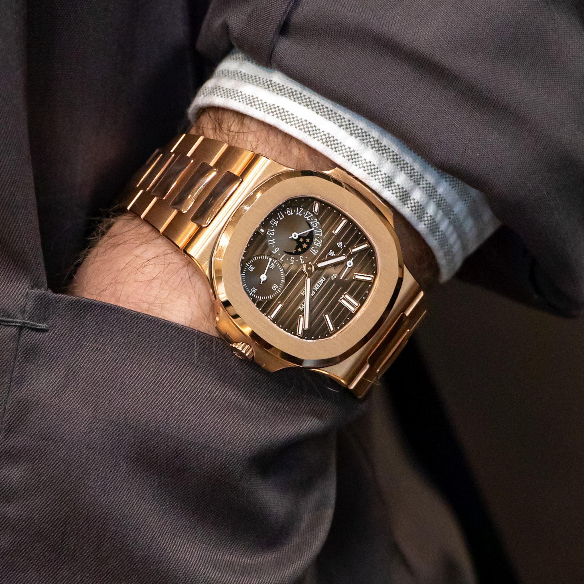 Gold watch on a wrist with a dark shirt background