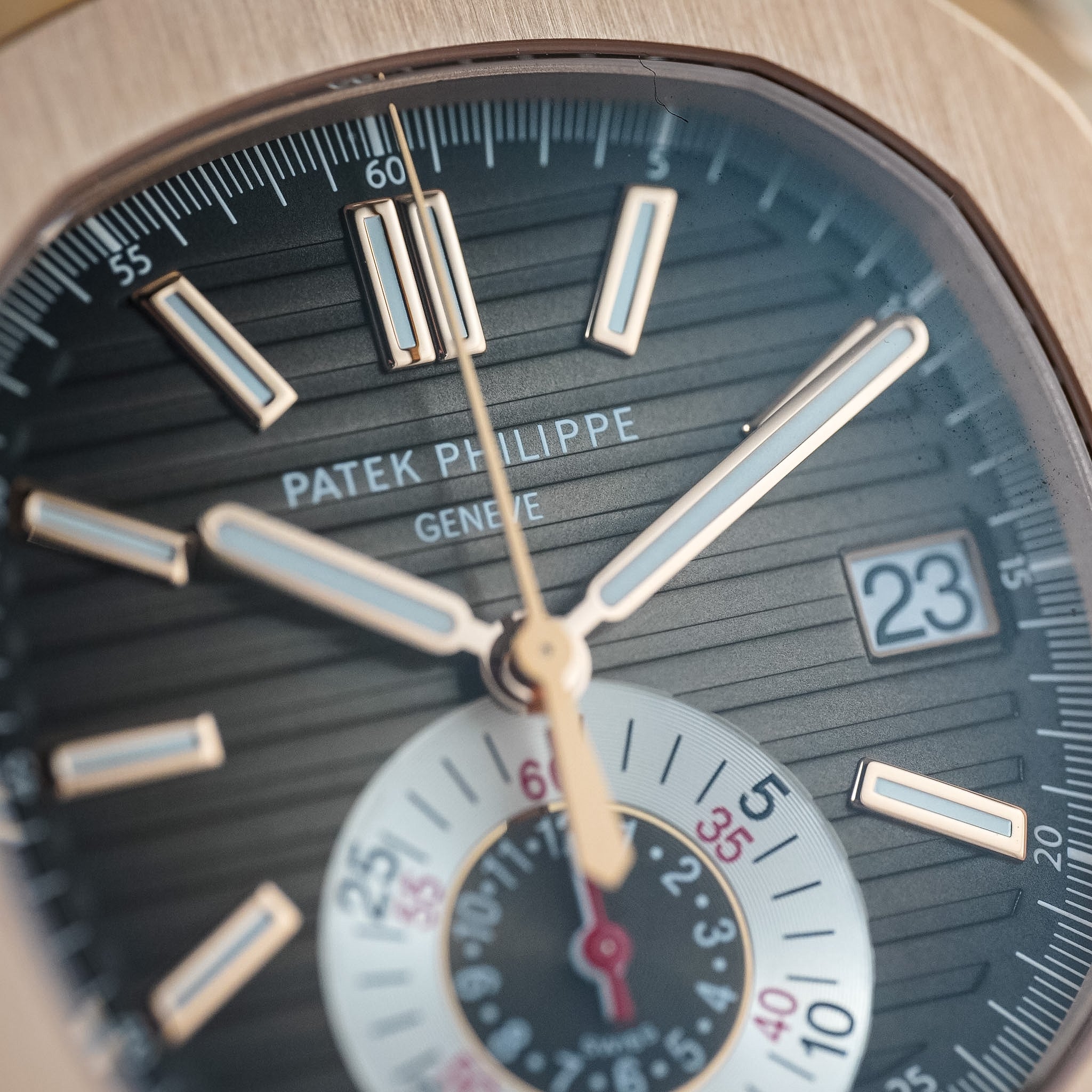 Close-up of a Patek Philippe watch face with gold hands and black dial.