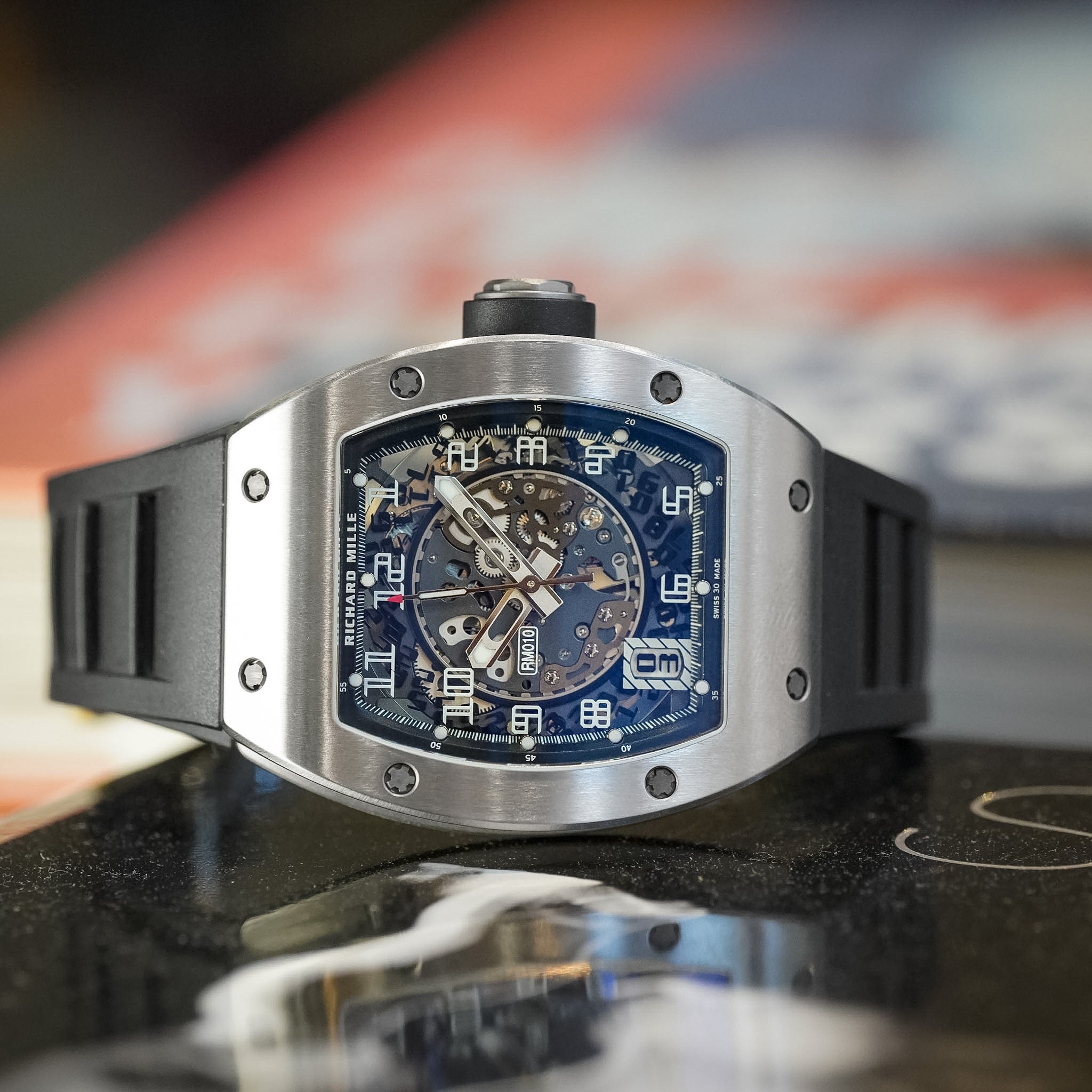 Luxury watch with a detailed face on a reflective surface, blurred background