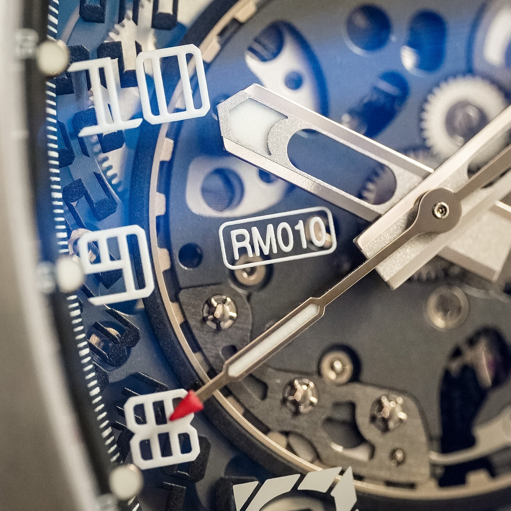 Close-up of a watch with 'RM010' branding on a blue background