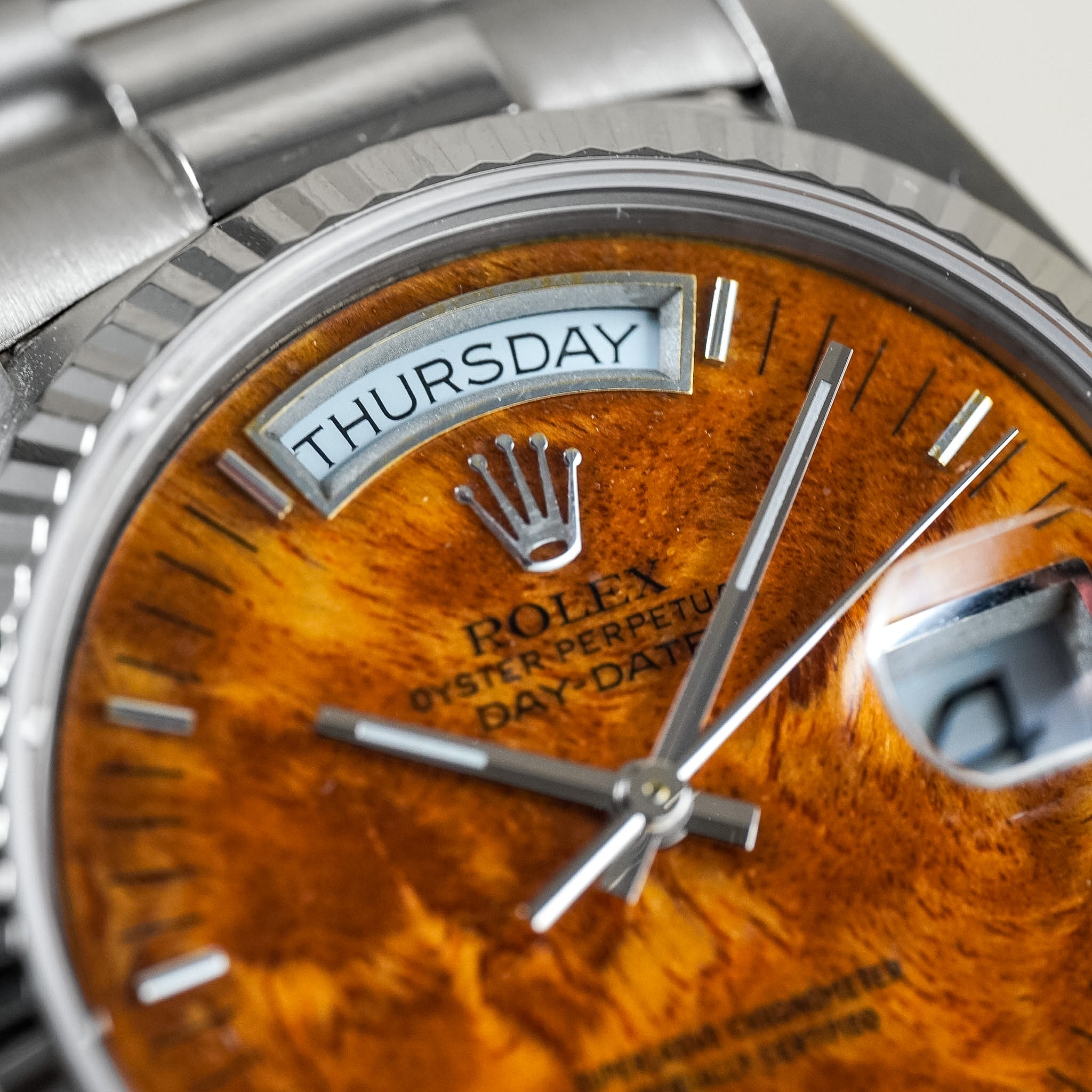 Close-up of a Rolex watch with a wooden dial and silver accents.