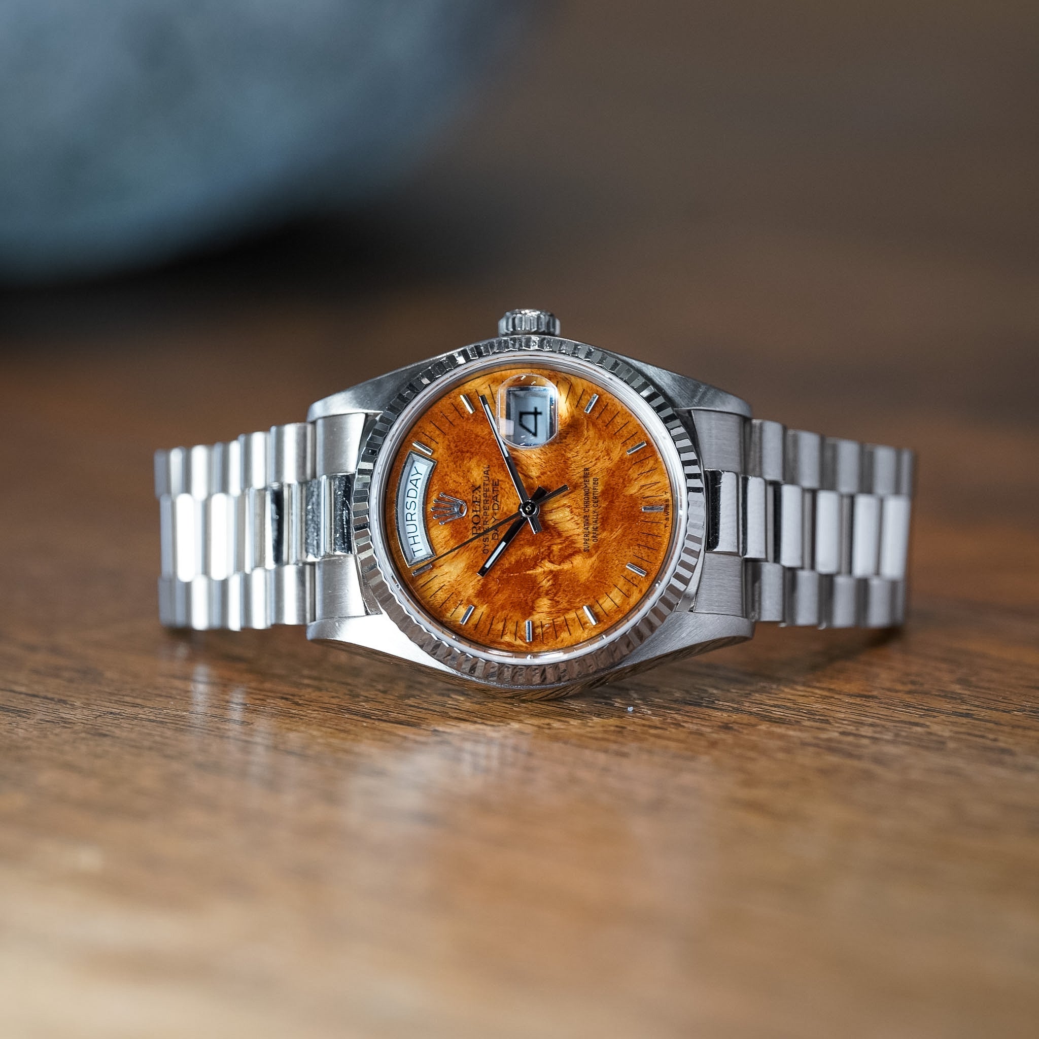 Silver wristwatch with a wooden dial on a wooden surface