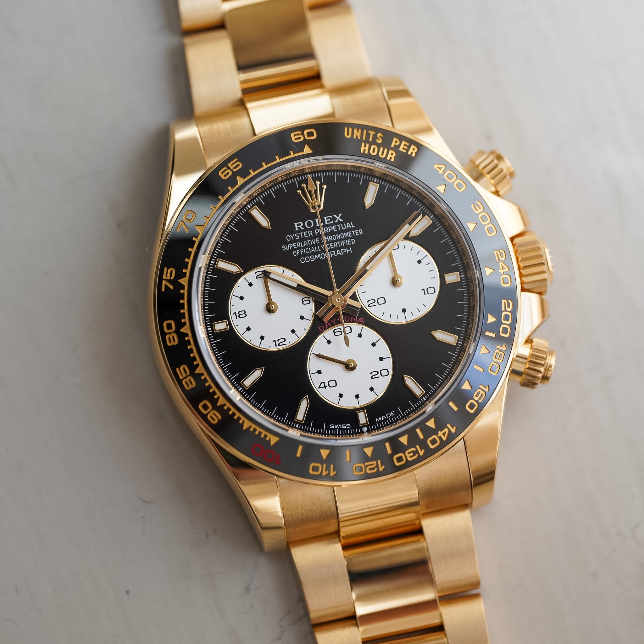 Gold watch with a black and white face on a light gray background