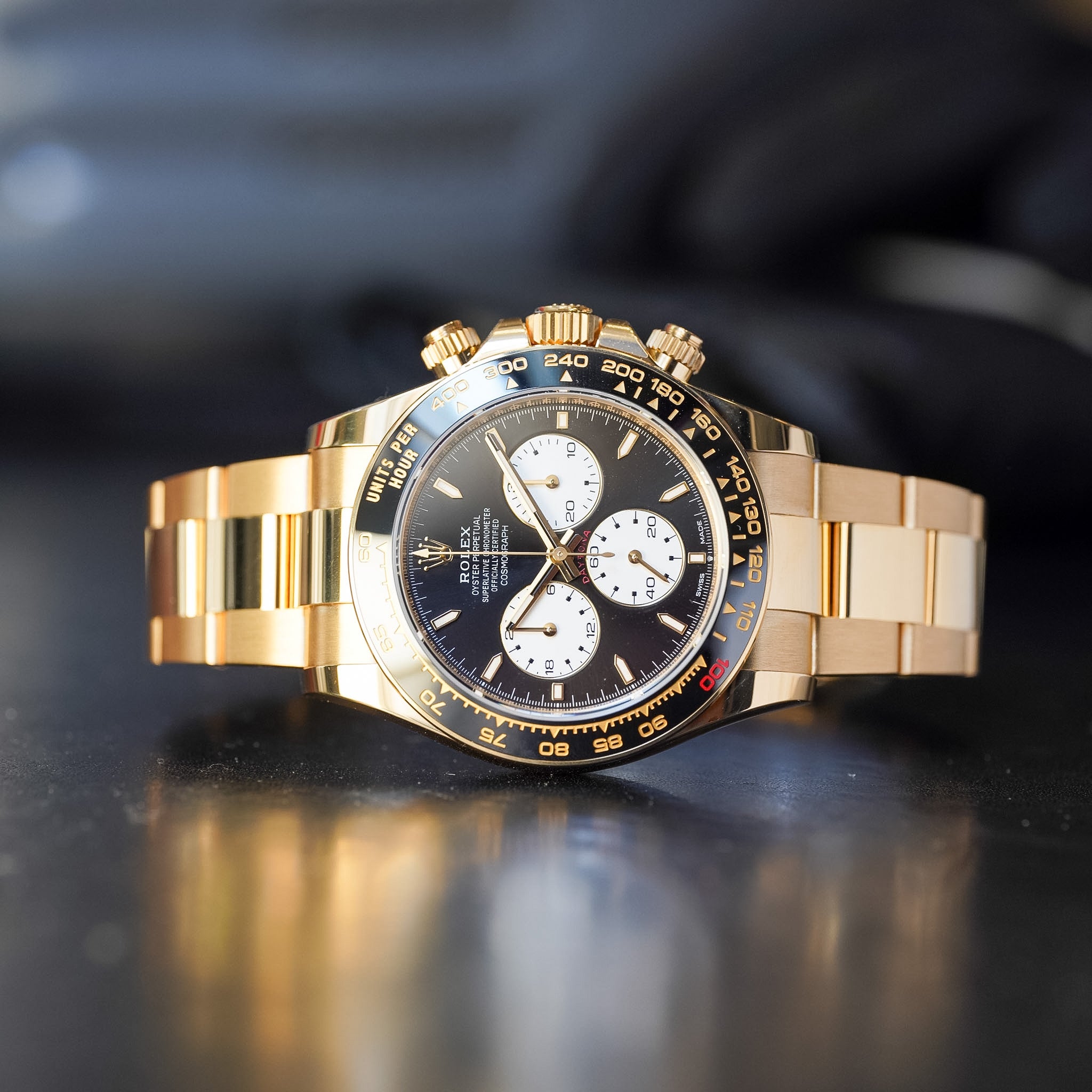 Gold wristwatch with a black face on a reflective surface