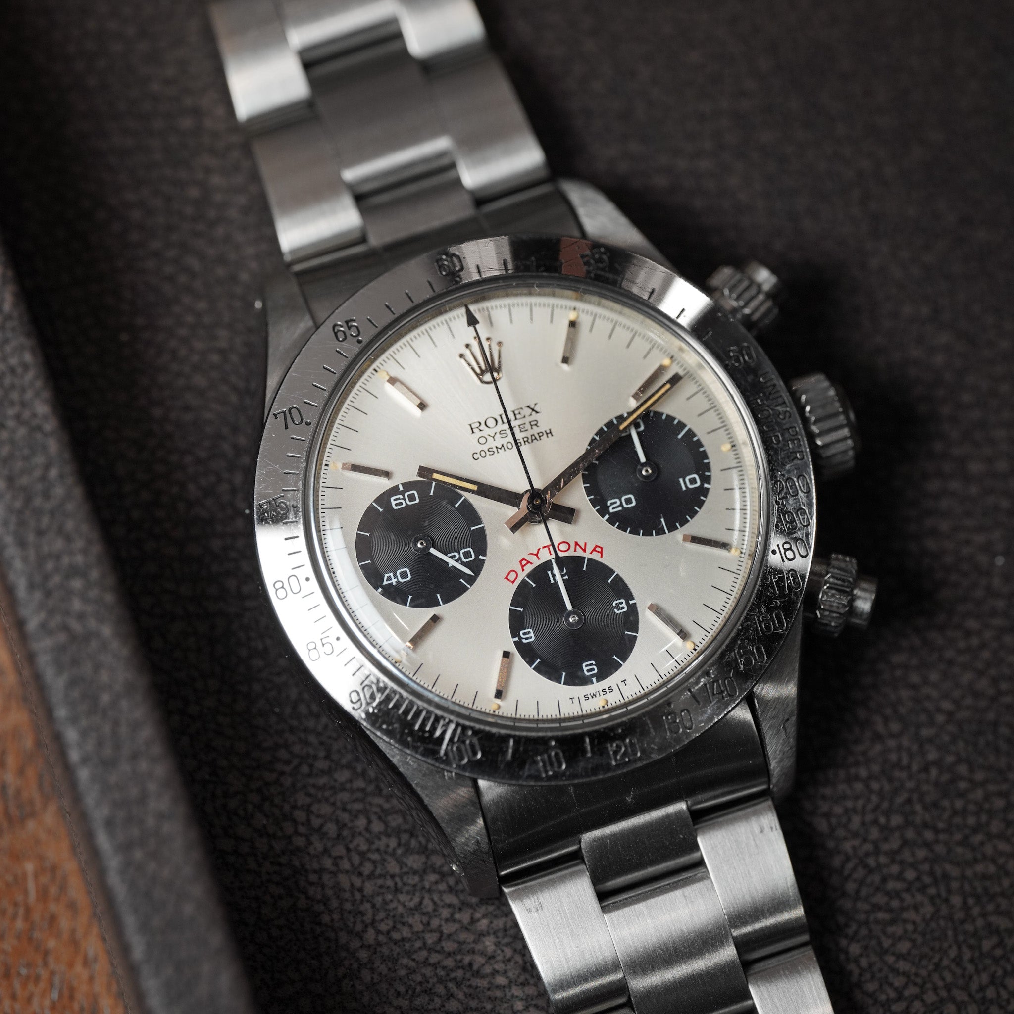 Steel Rolex watch with a silver dial on a dark tray