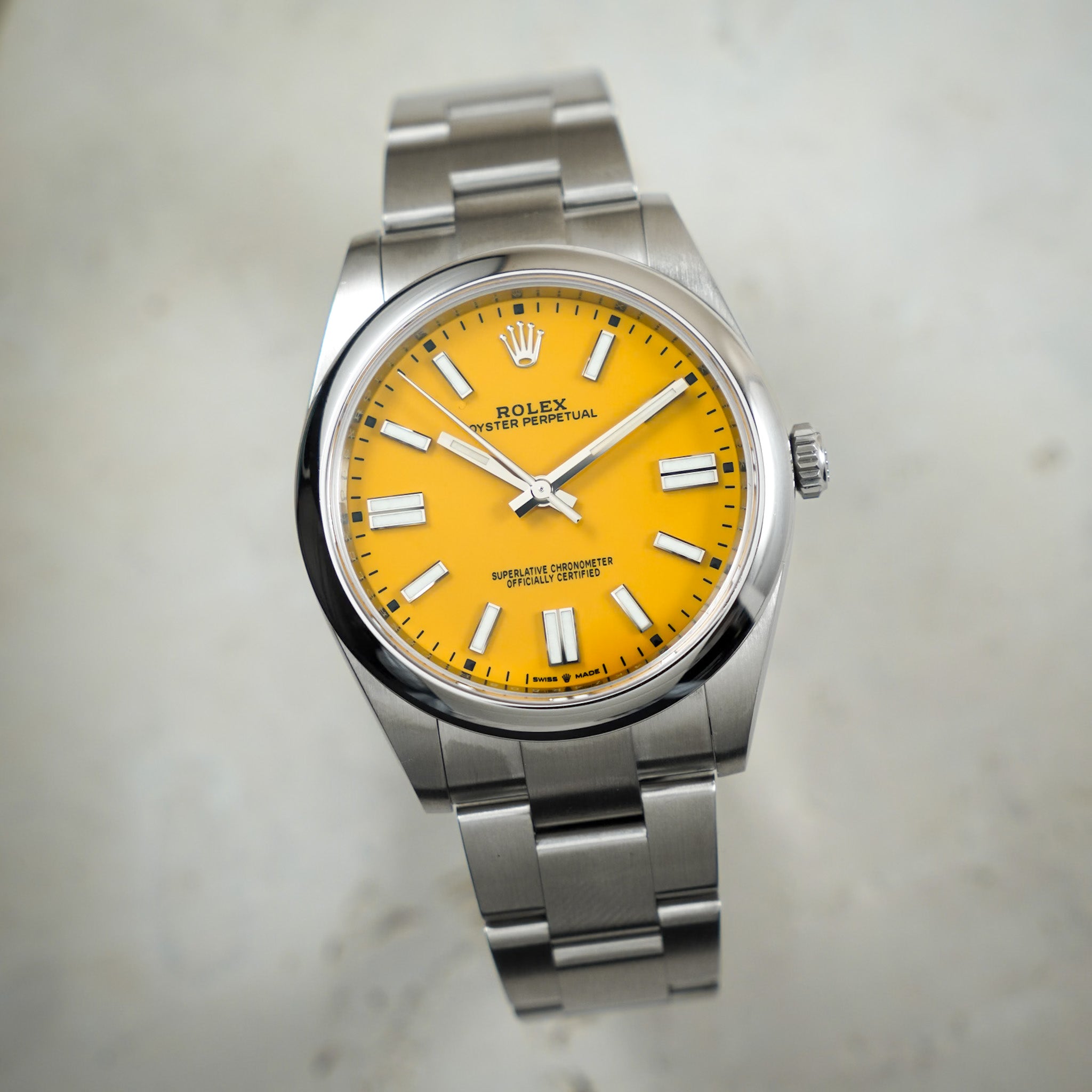 Rolex watch with yellow face and silver bracelet on a light gray background