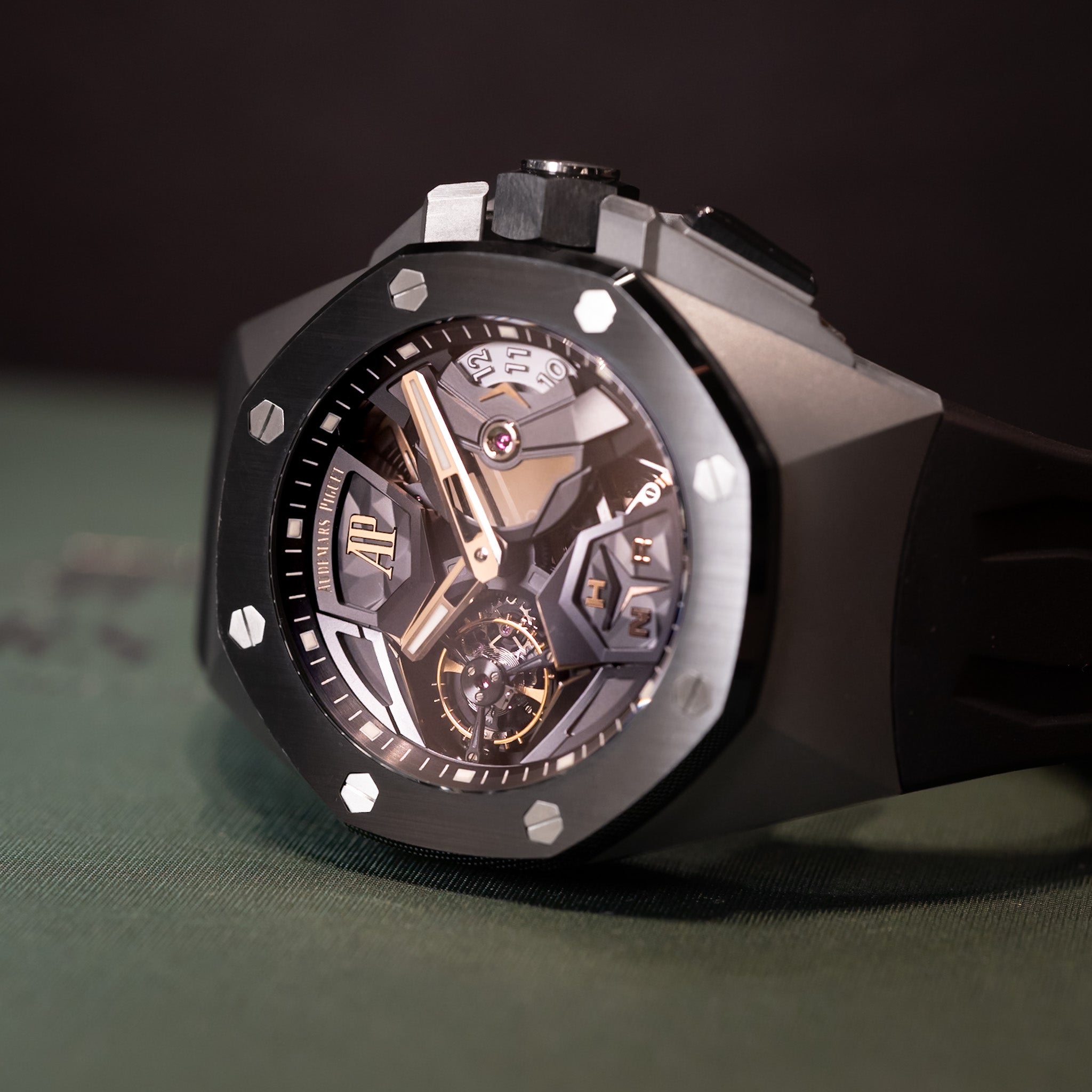 Luxury watch with a black case and transparent face on a green surface