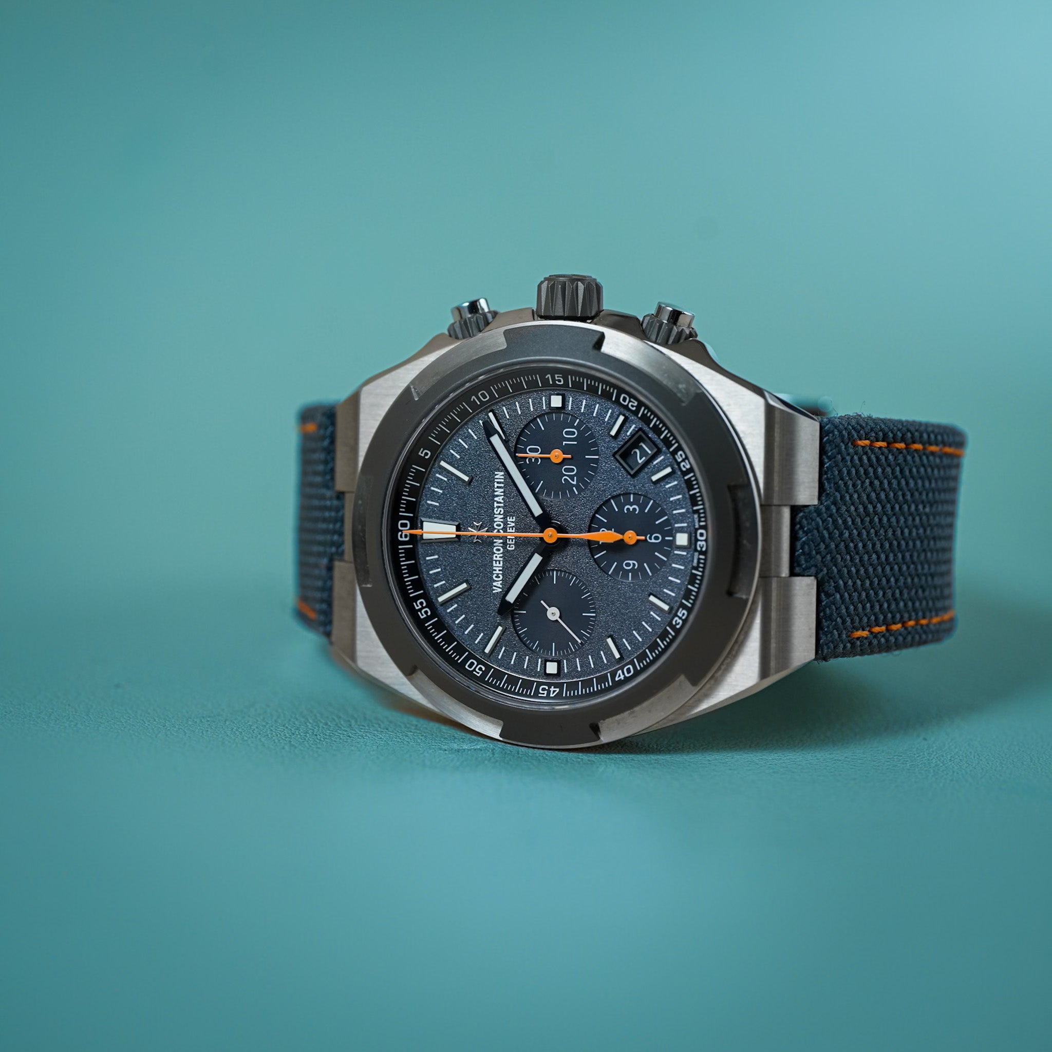 Wristwatch with blue strap and dark face on a teal background
